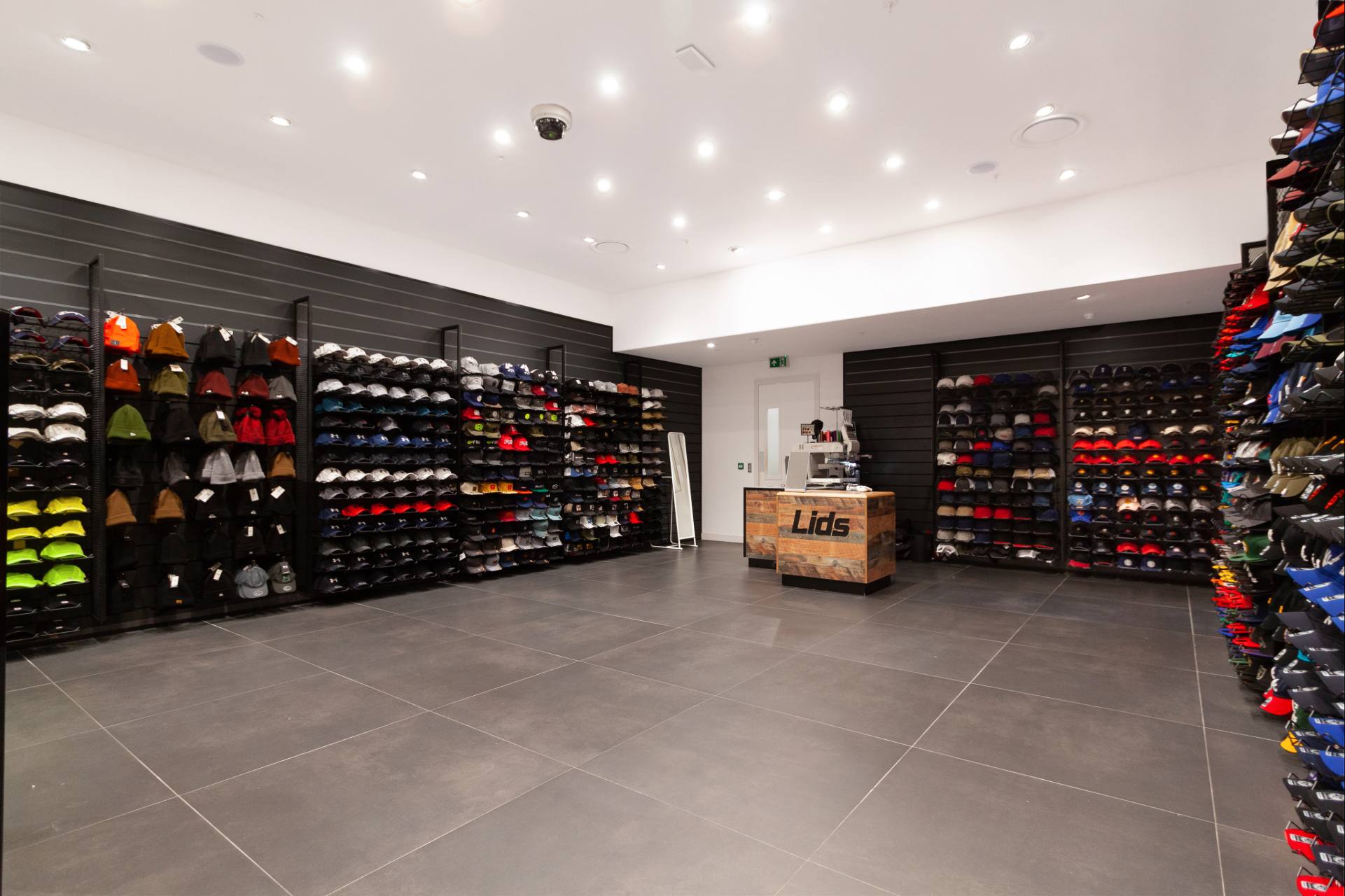 Mur noir, rangement, sol gris, commode en bois clair avec logo