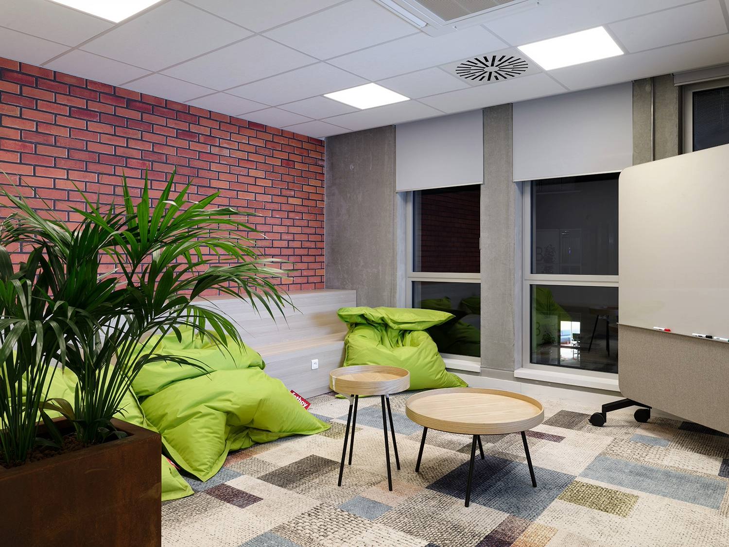 Parquet en bois clair, mur de brique rouge, fenêtres, fauteuil vert