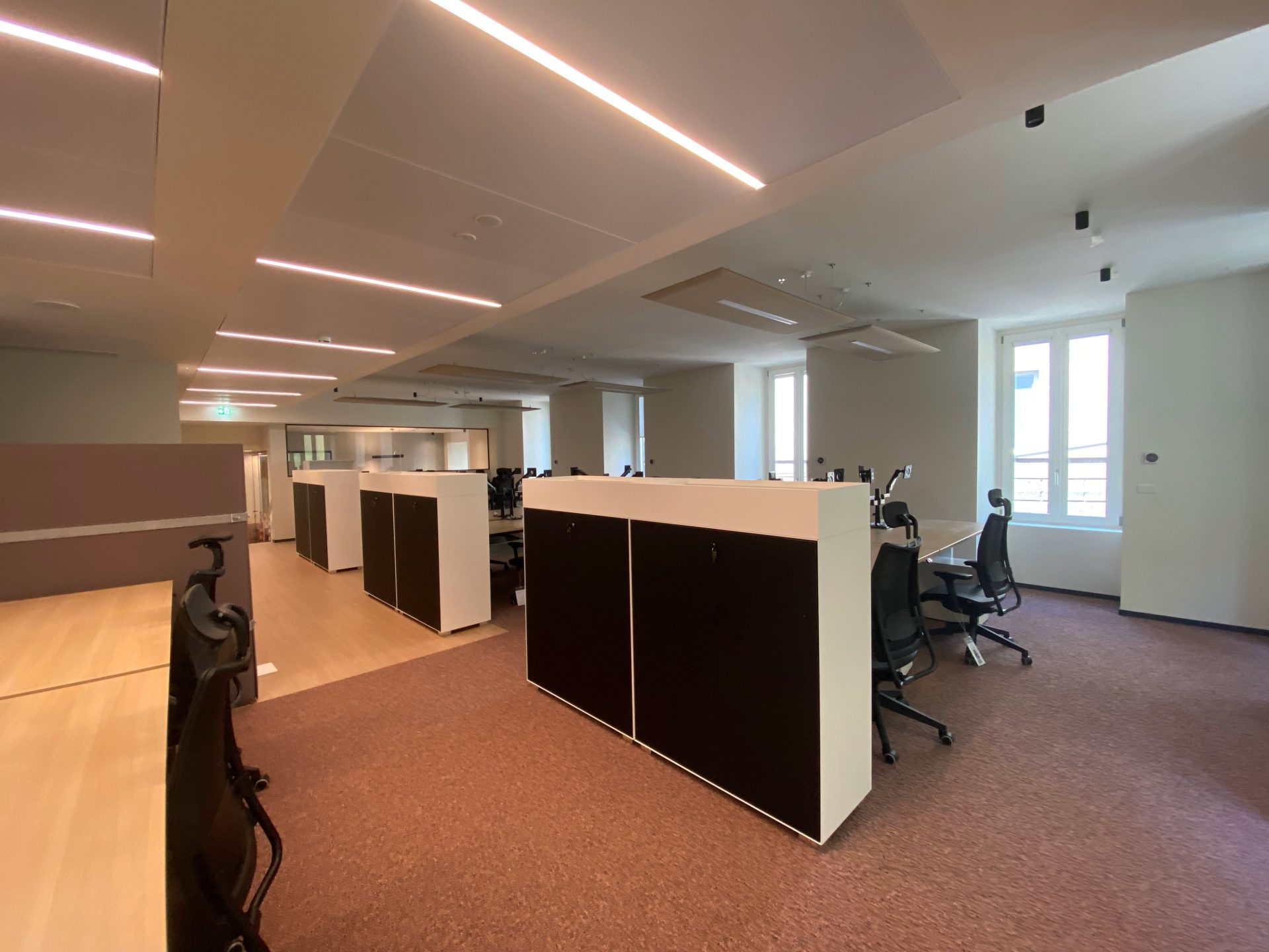 Coworking, meuble noir et blanc, parquet en bois clair, moquette rouge