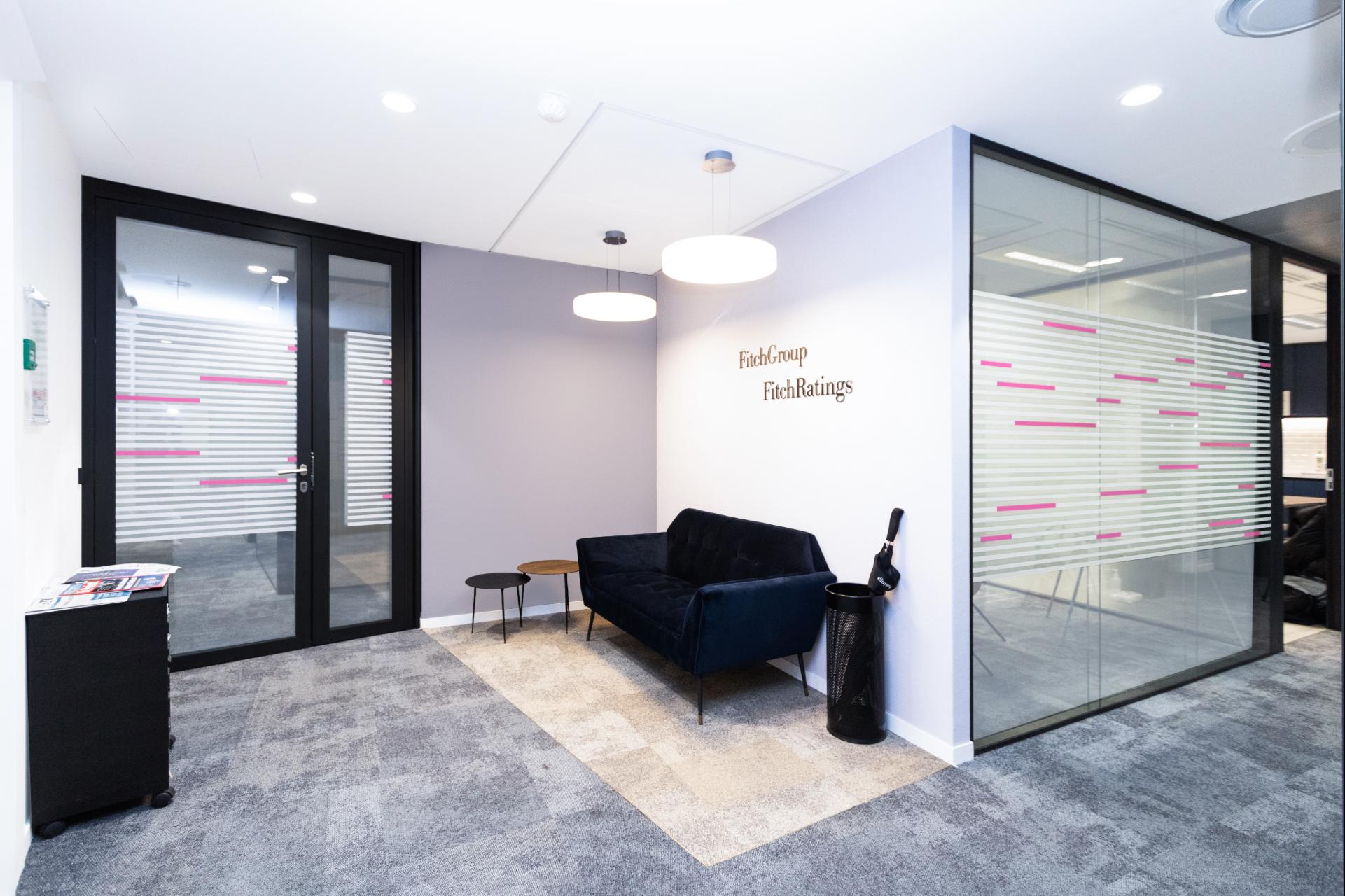 Espace d'accueil avec canapé d'attente, logo au mur