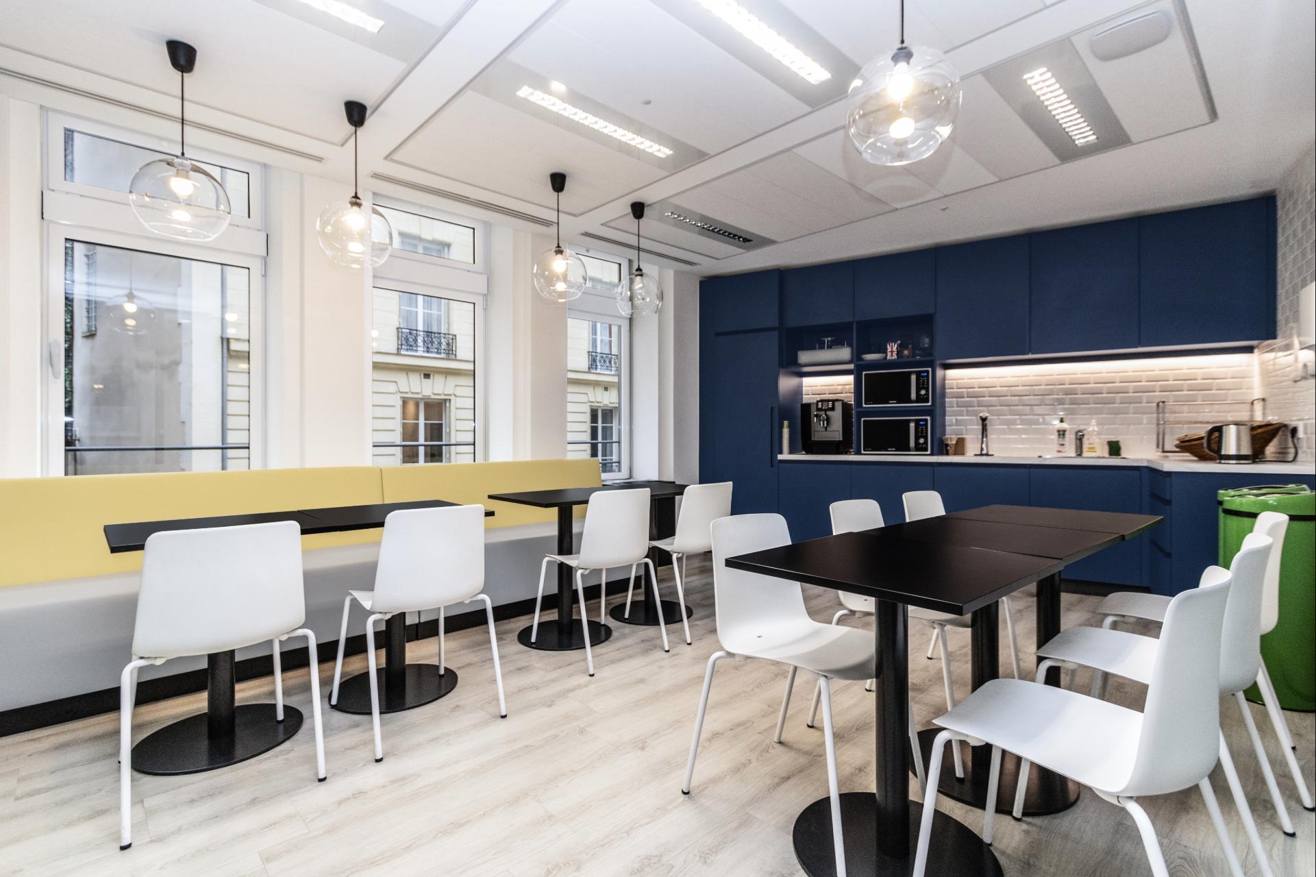 Espace de restauration dans les tons blancs, bleu marine et jaune pâle.