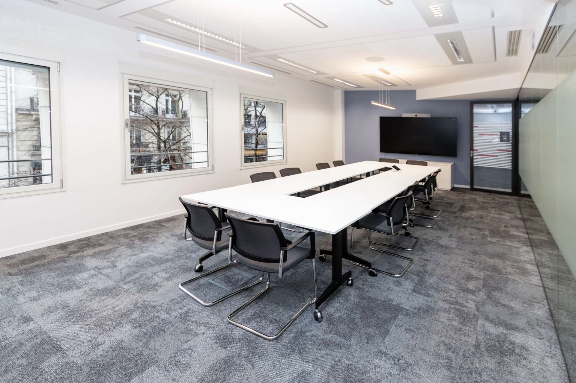 Salle de réunion avec table blanche, moquette grise au sol et murs clairs