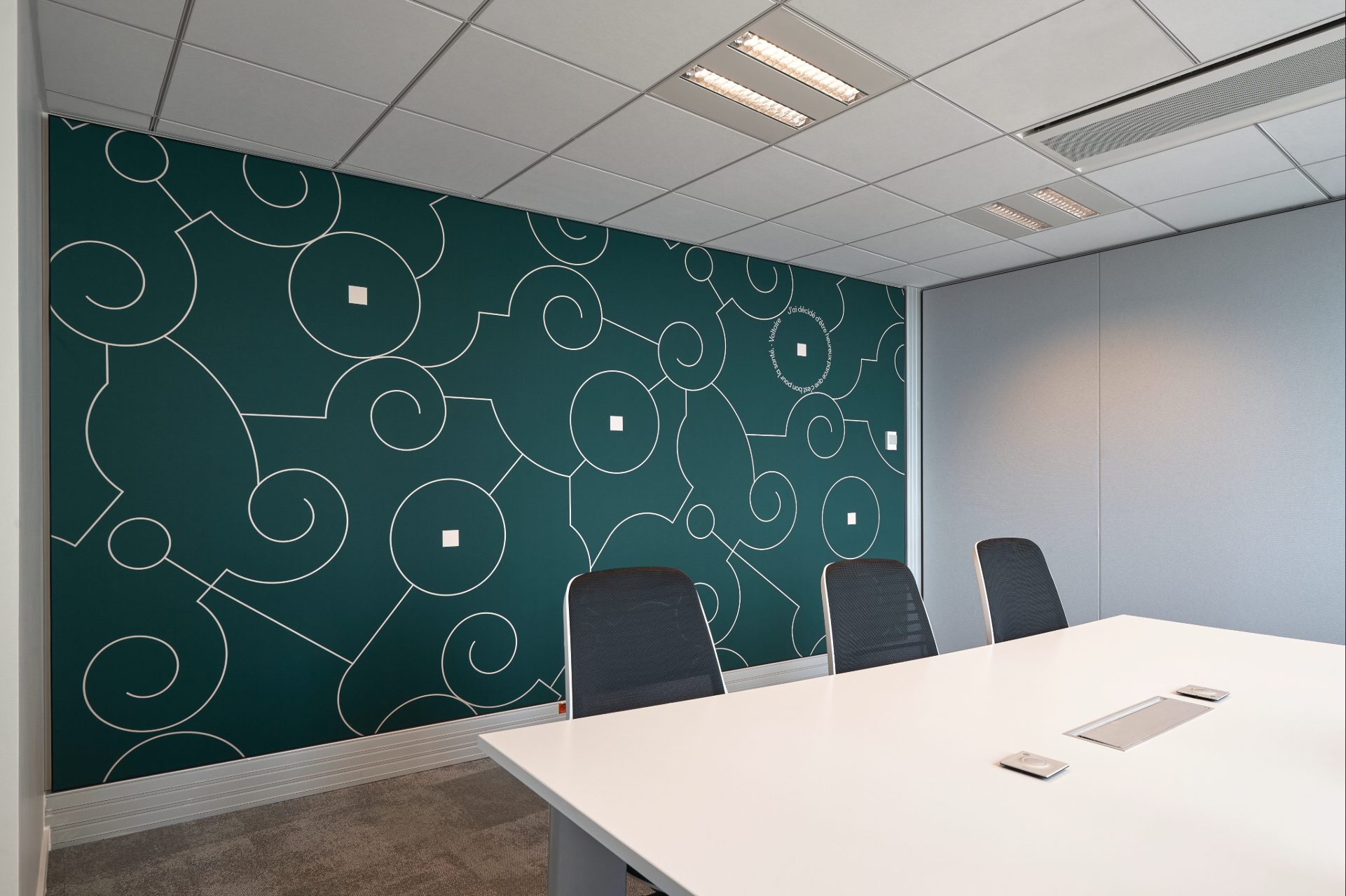 Salle de réunion, mur vert sapin avec décoration, table blanche et siège noir