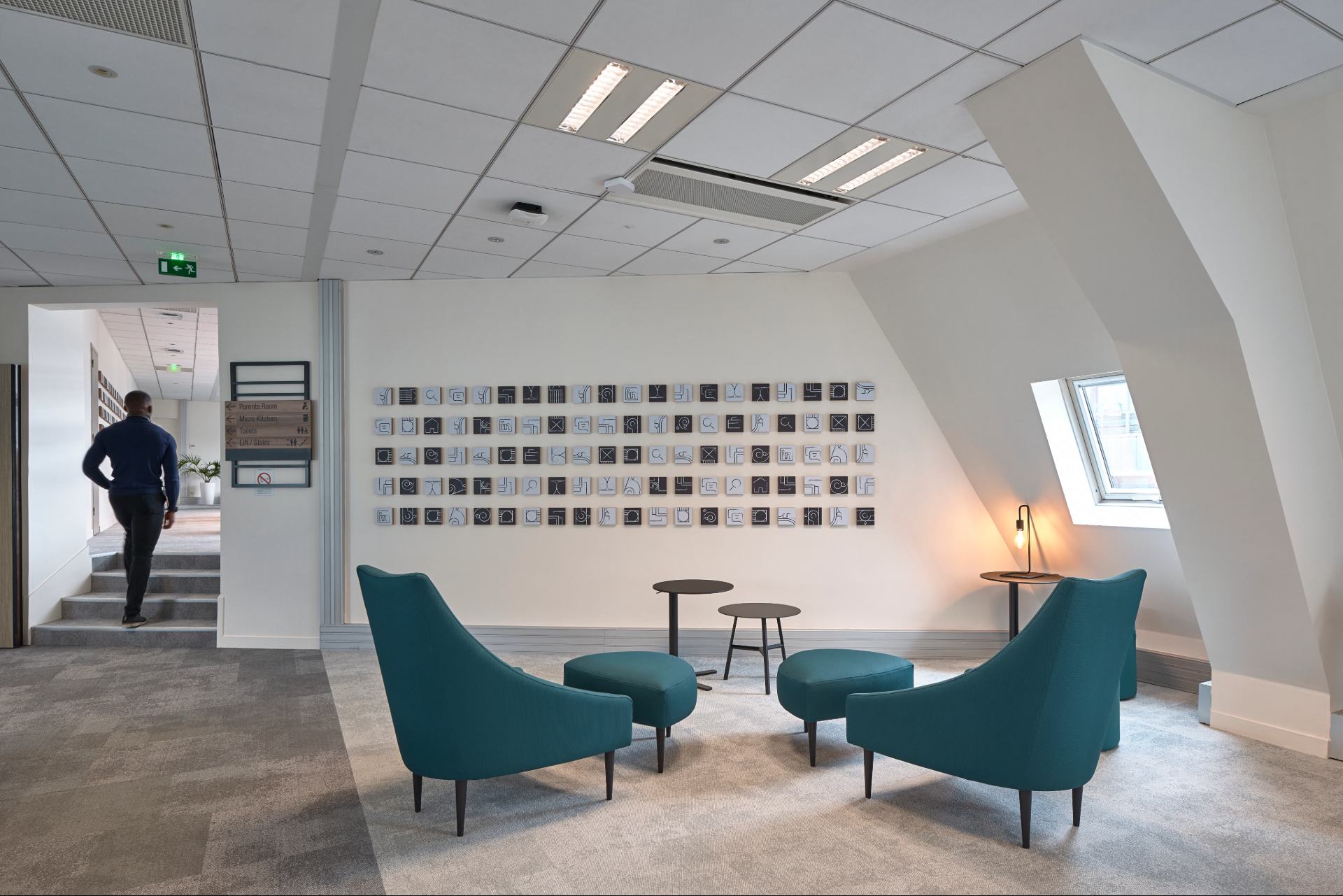 Pièce avec fauteuils bleus, décoration murale noire et blanche