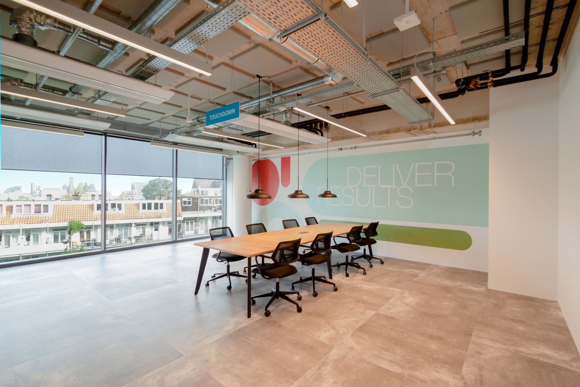 Salle de réunion spacieuse avec un mur décoré de formes colorées, de grande baies vitrées apportent de la lumière