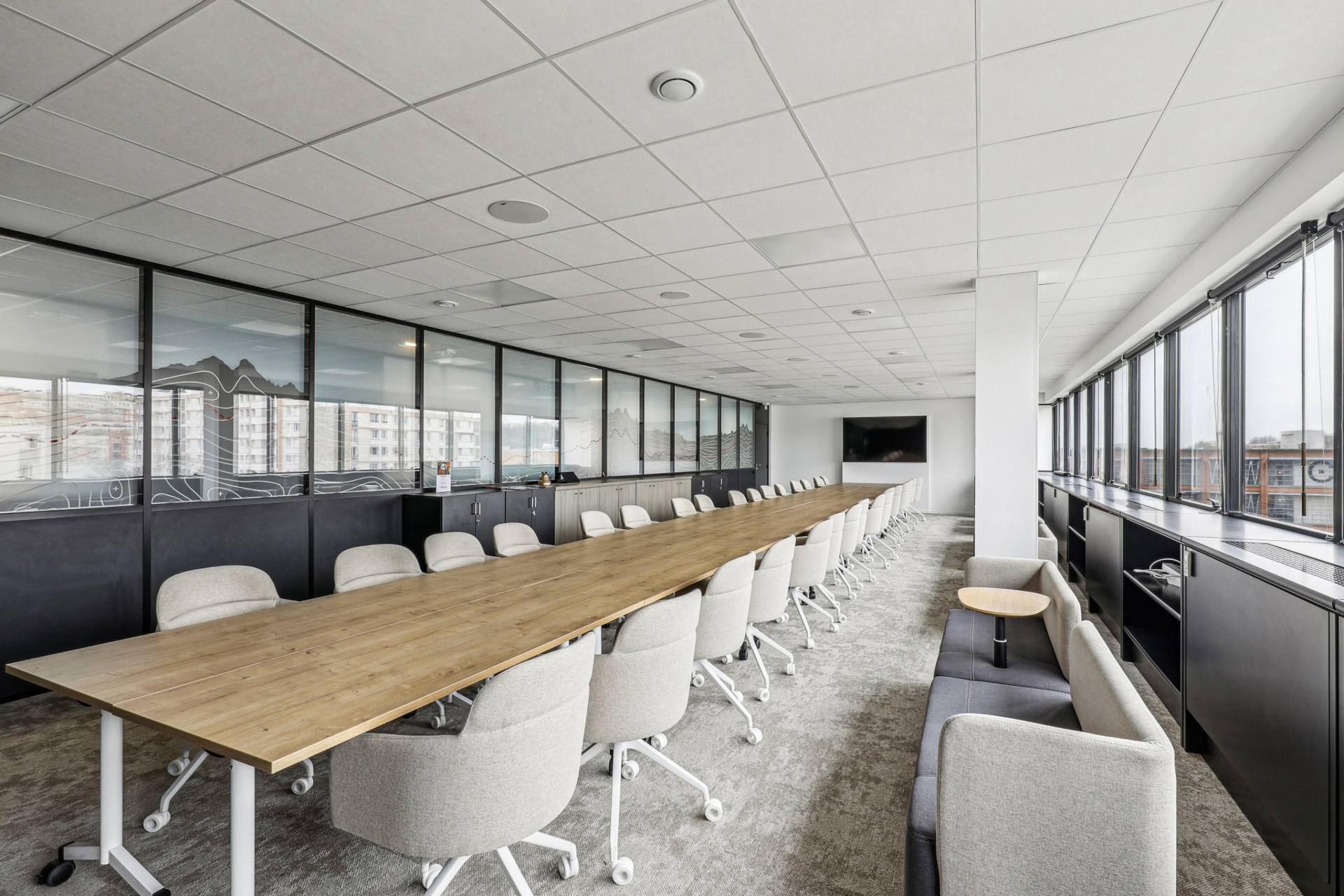 Grande salle de réunion blanche et gris clair, table en bois clair