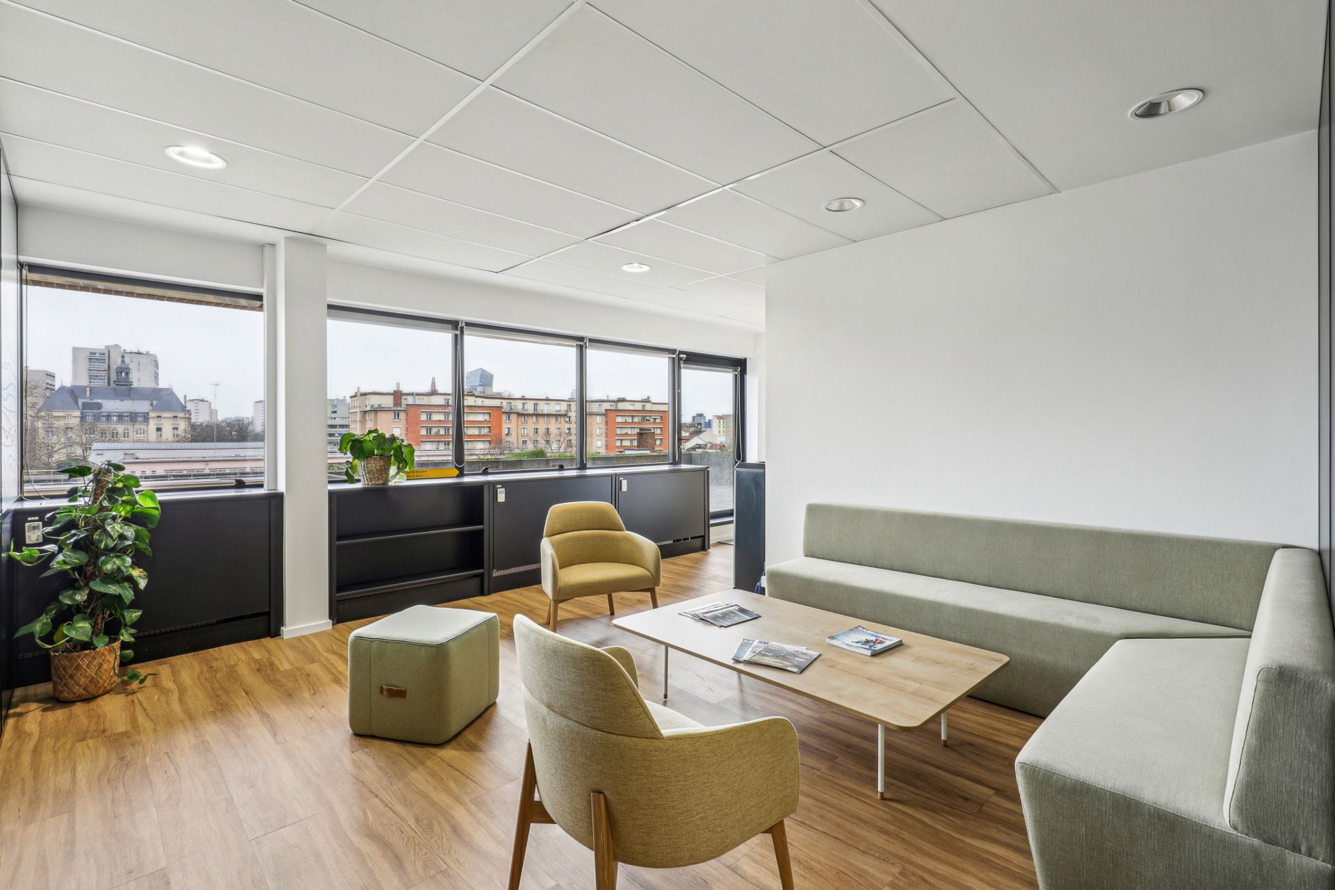 Salon avec grand canapé d'angle, 2 fauteuils et un pouf.
