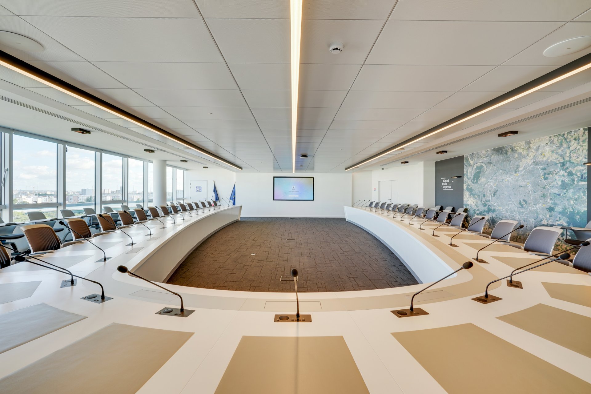 Grande salle de réunion pour environ 40 personnes, disposition en U, avec un écran dans le fond