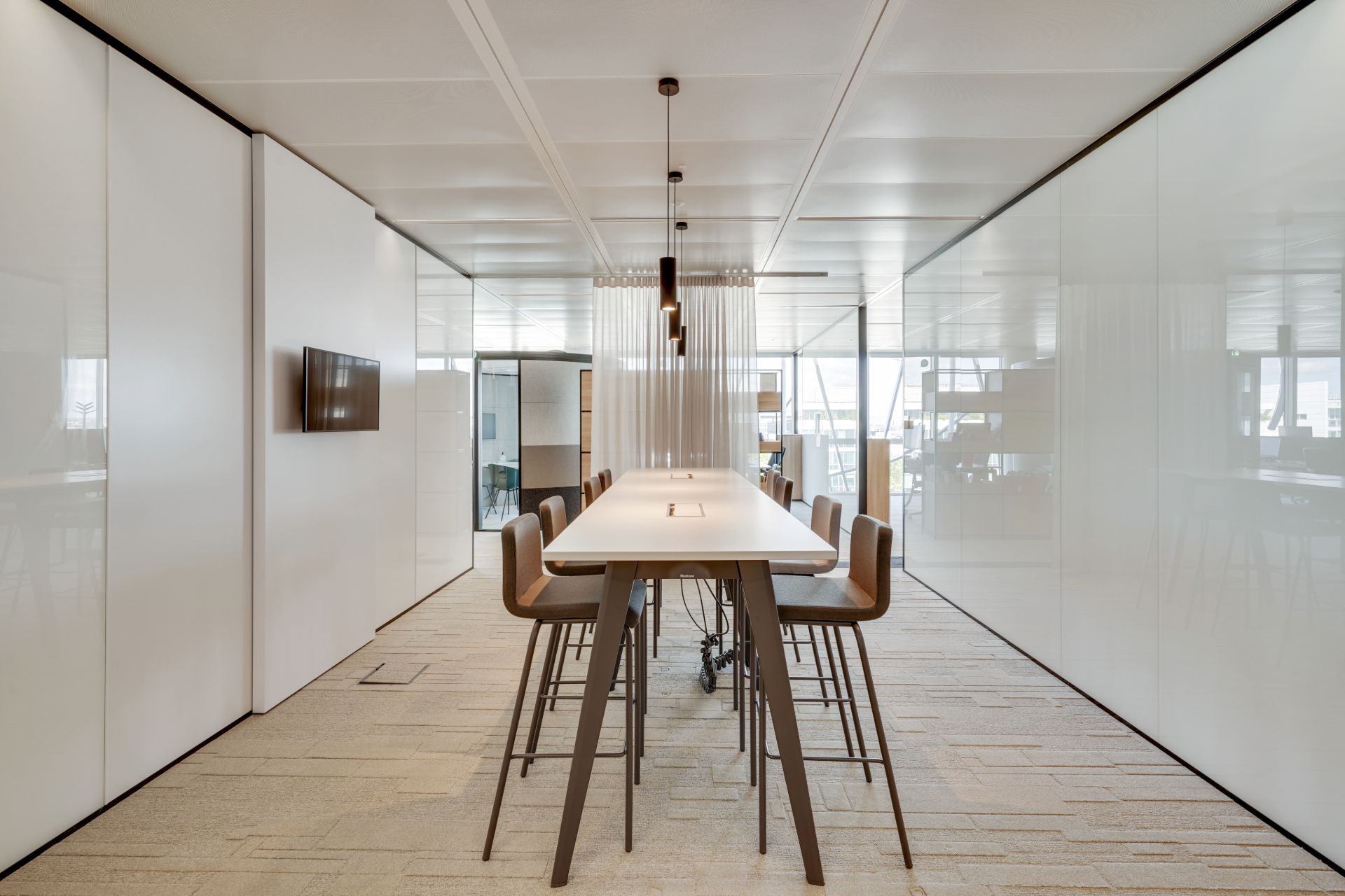 Salle de réunion ou de coworking, avec table et chaises hautes.