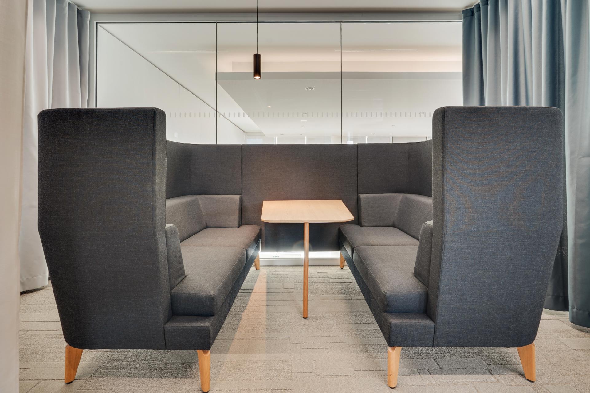 Espace de réunion informelle, formée d'un seul bloc avec 2 banquettes grises foncé et une petite table centrale en bois clair
