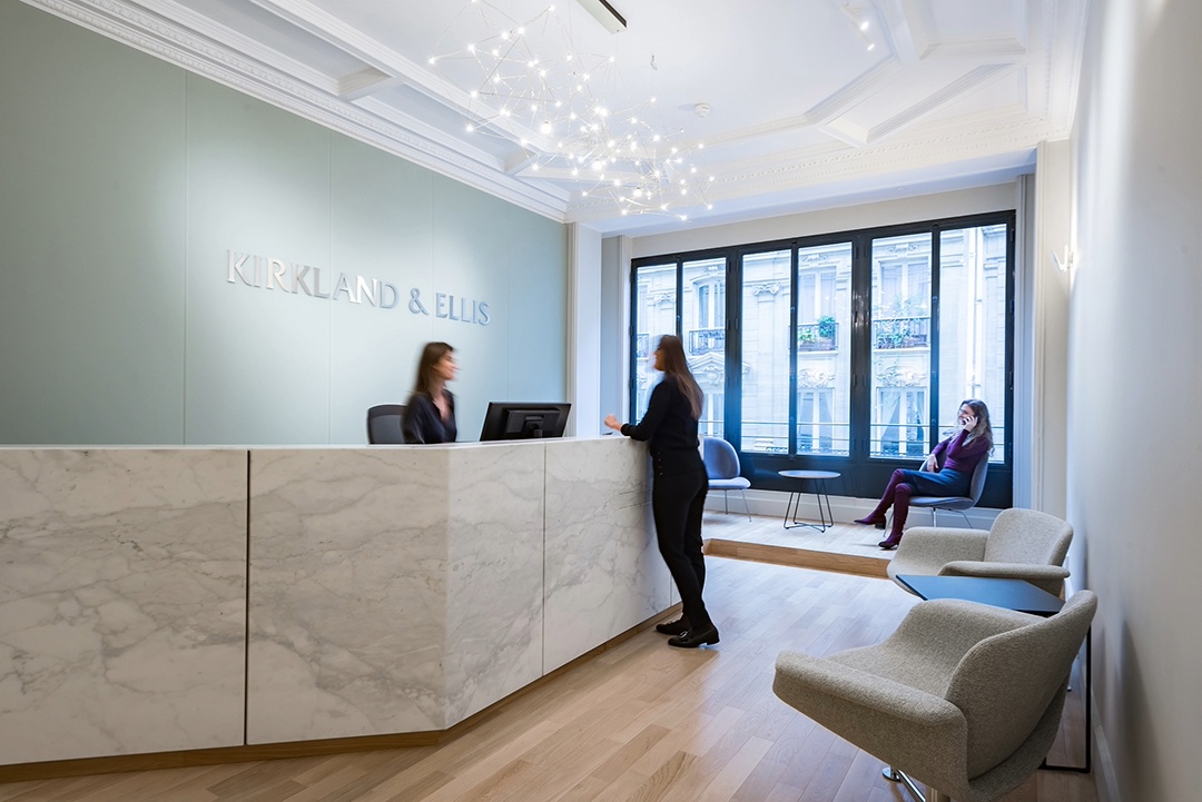 Accueil chez Kirkland & Ellis, mur vert pâle, desk d'acceuil impression marbre blanc, grande baie vitrée et espace d'attente