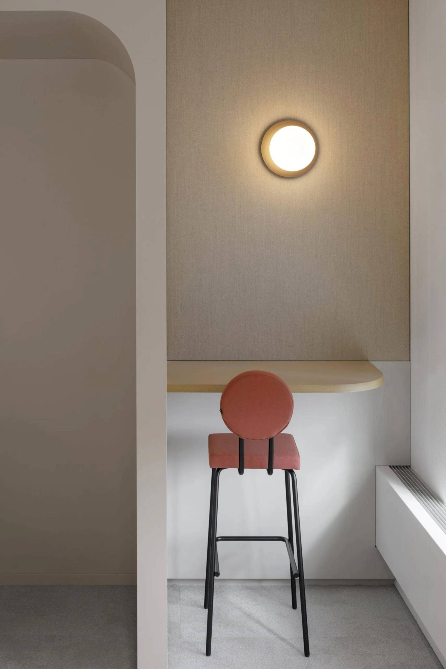 Petit bureau isolé pour rdv visio ou téléphonique, mur beige, applique lumineuse ronde au mur et chaise haute couleur terracotta qui contraste avec l'ensemble