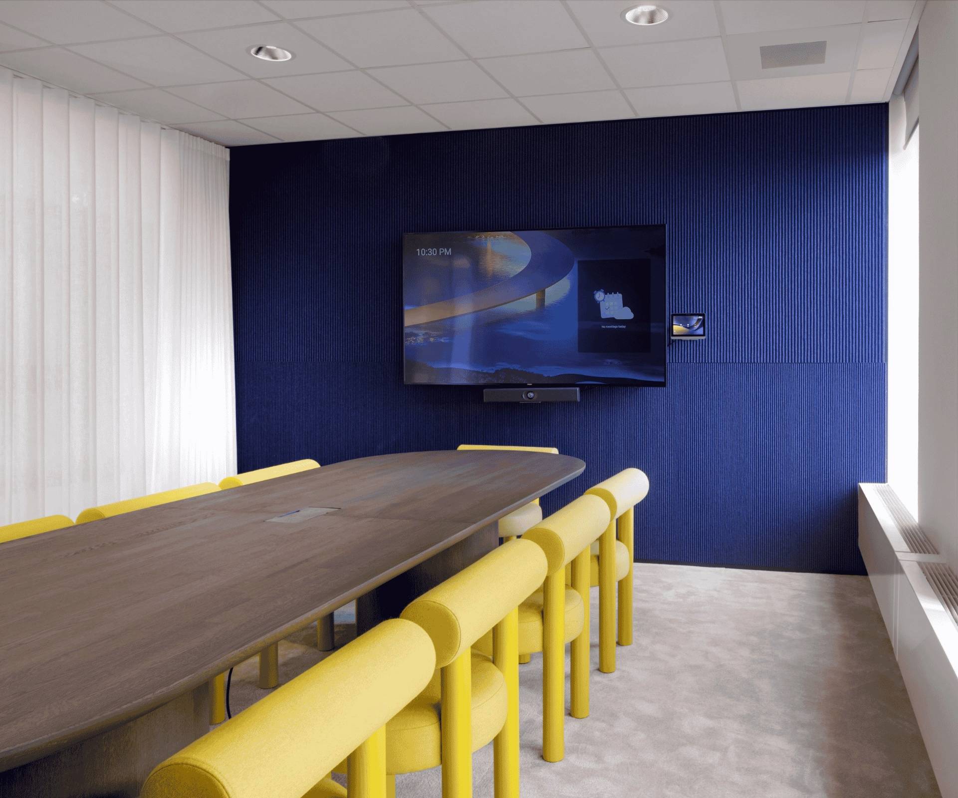 Salle de réunion avec mur bleu foncé, table en bois foncé et chaises jaunes