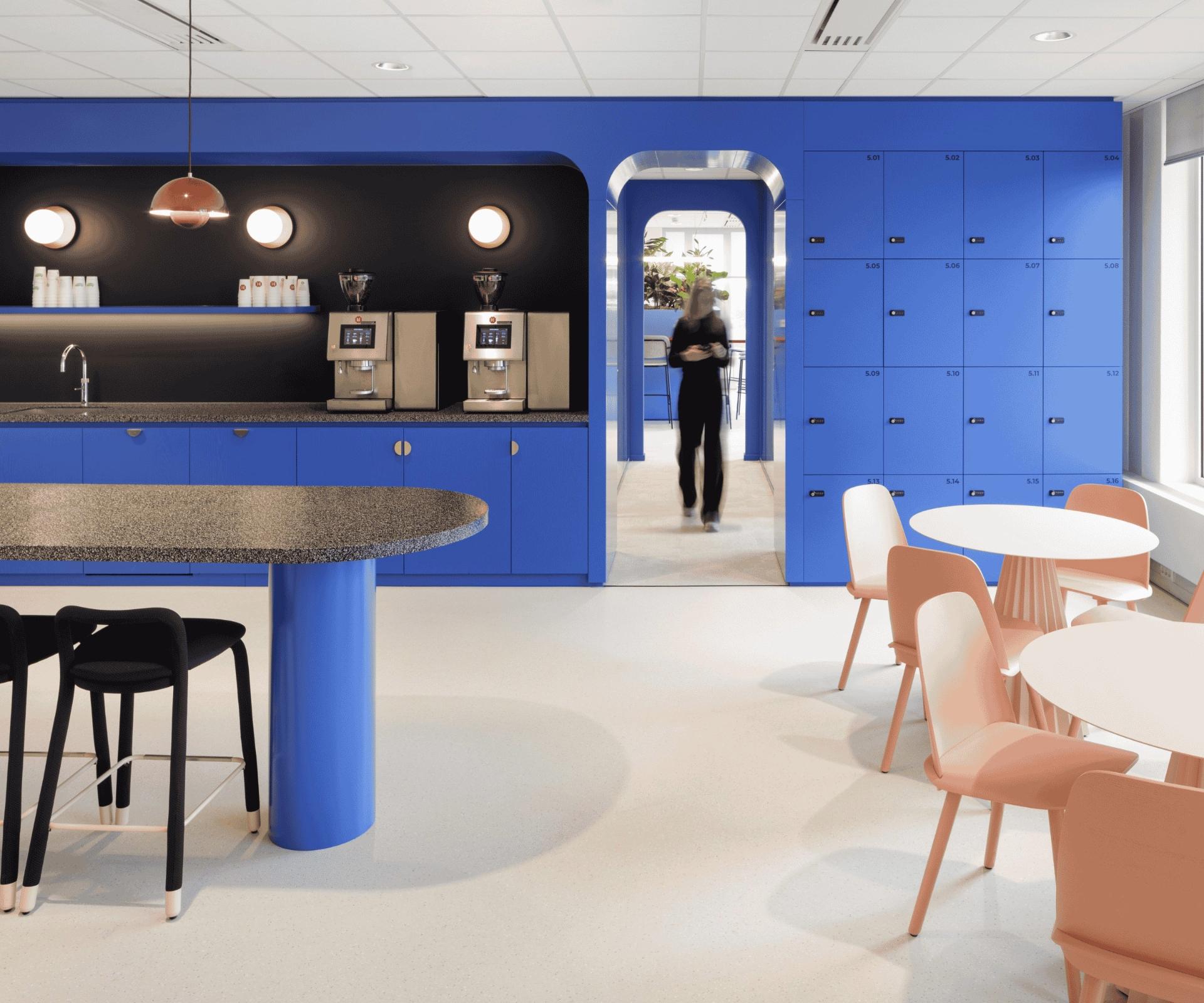 Cafétéria avec mur et mobilier bleu, sol de couleur clair et de petites tables et chaises orange pâle