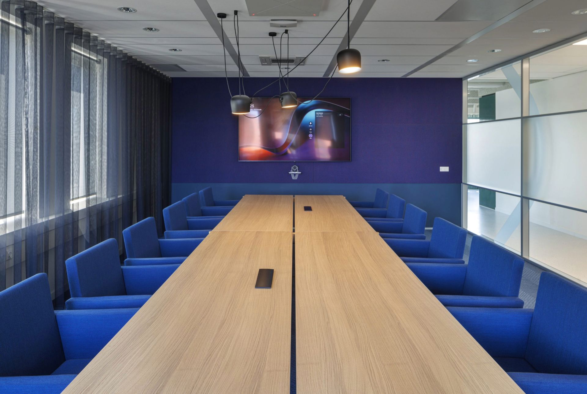 Grande salle de réunion, sièges bleus foncé et grande table en bois clair