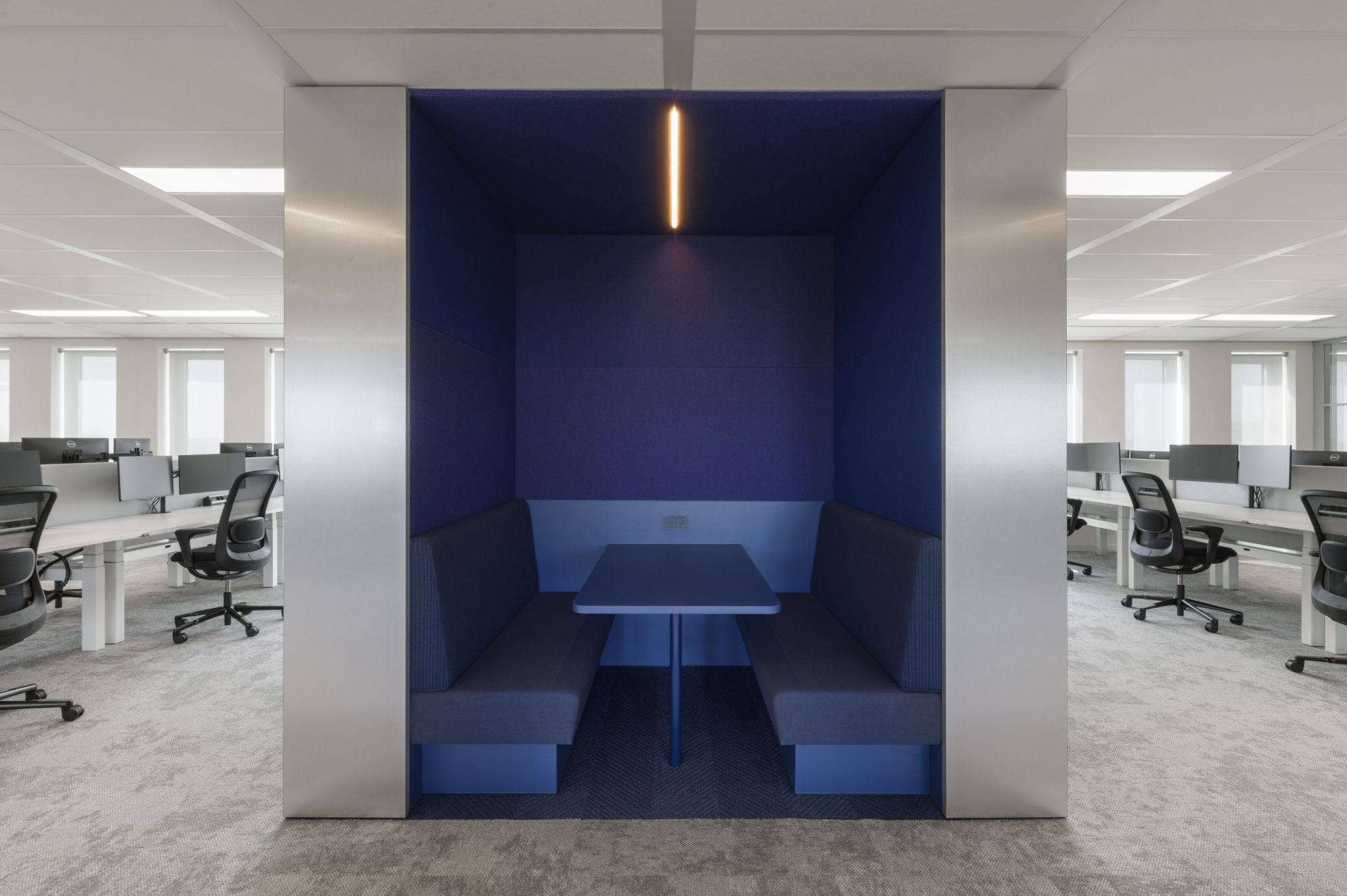 Bulle avec mur et mobilier bleu foncé, elle se démarque du reste de l'open space qui est dans les tons gris clair