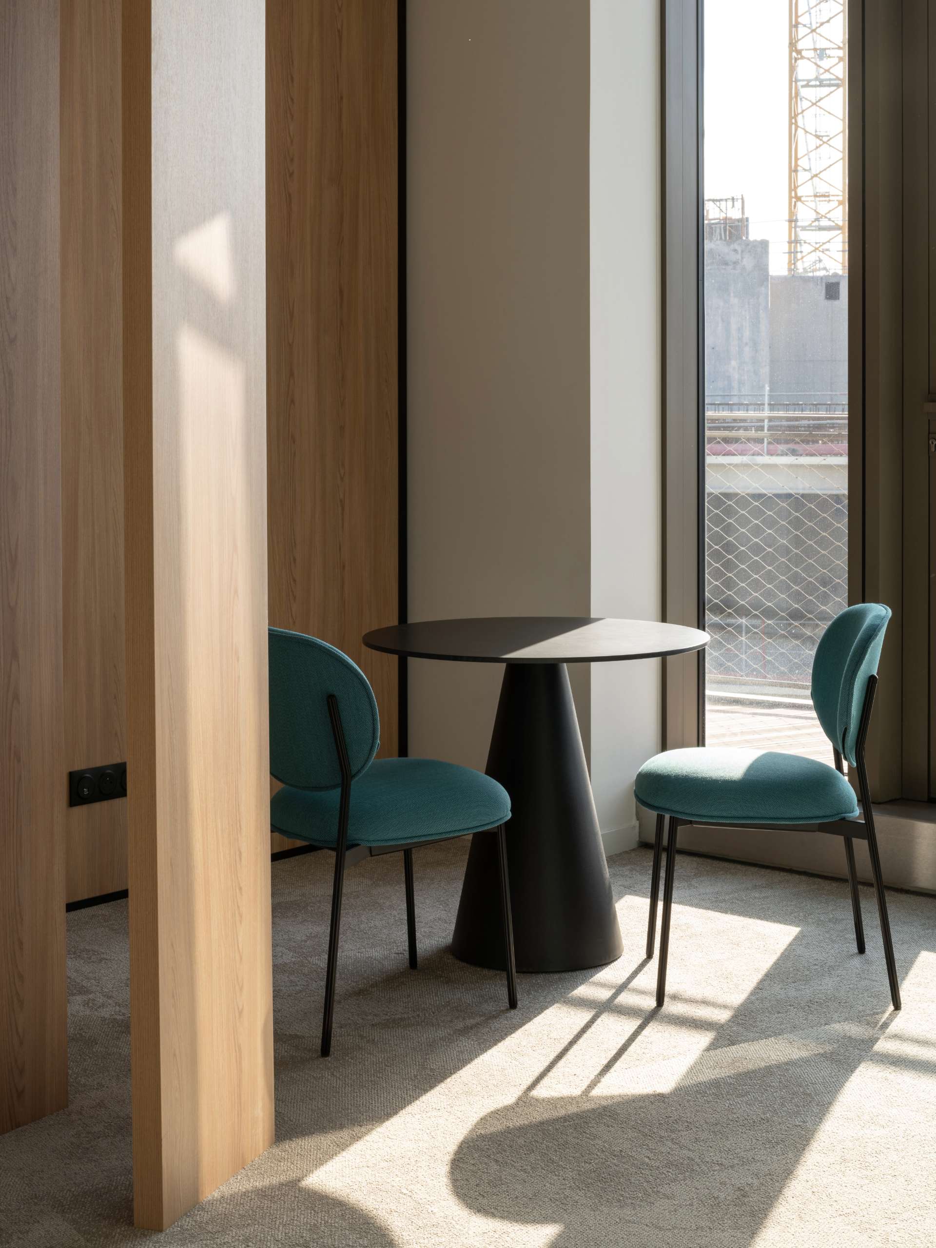 Petit espace d'échange avec 2 chaises bleu vert et une petite table