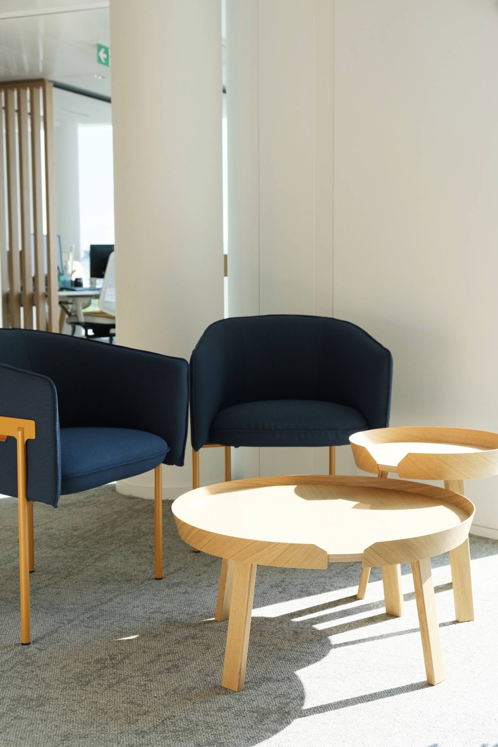 Un espace avec 2 fauteuils bleus foncé et table basse en bois clair
