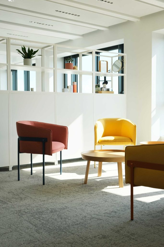 Petit salon avec fauteuils rouge et jaune, table basse en bois clair, chez NAOS, par Parella