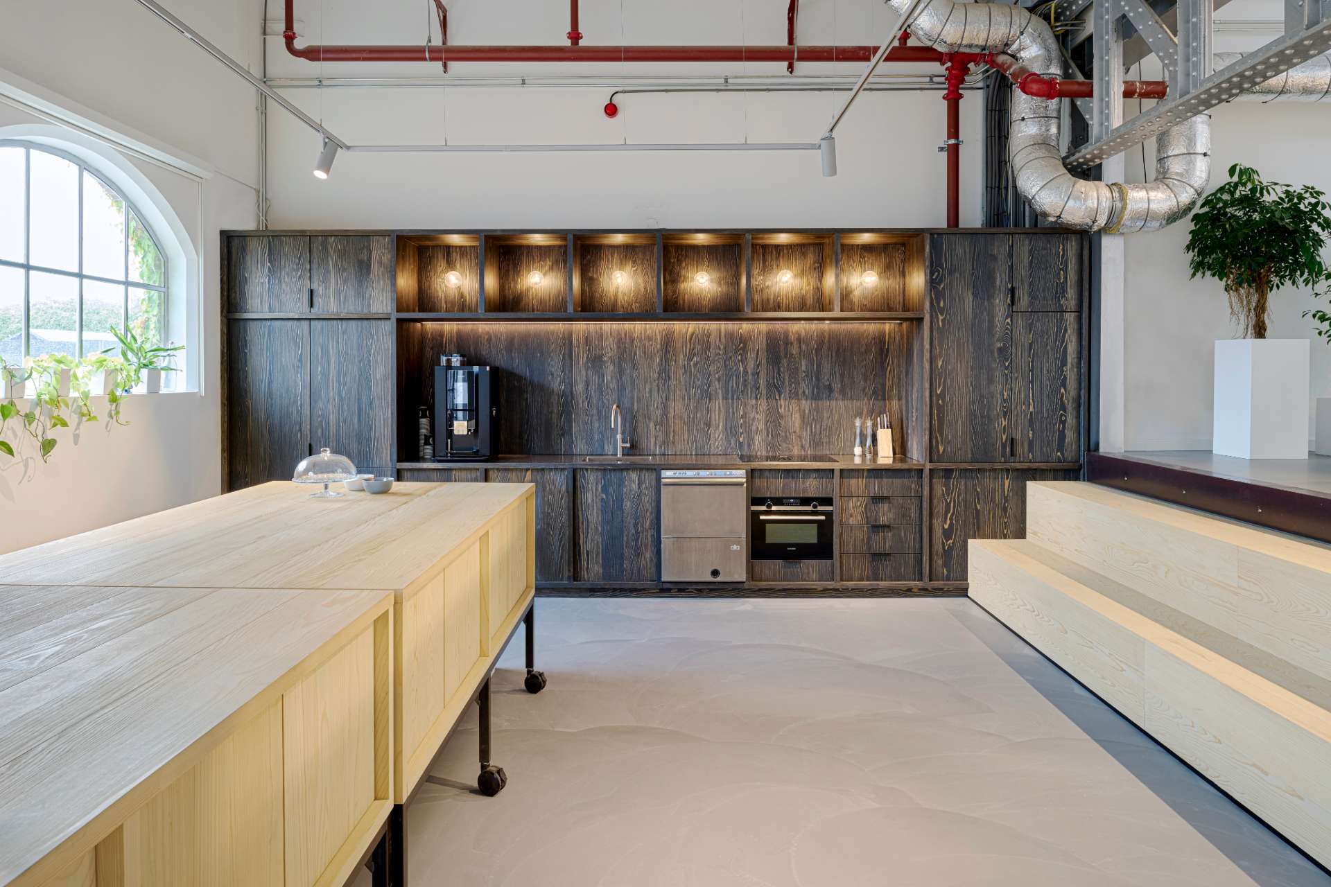 Espace cafétéria avec un grand meuble en bois foncé et luminaires incrustés