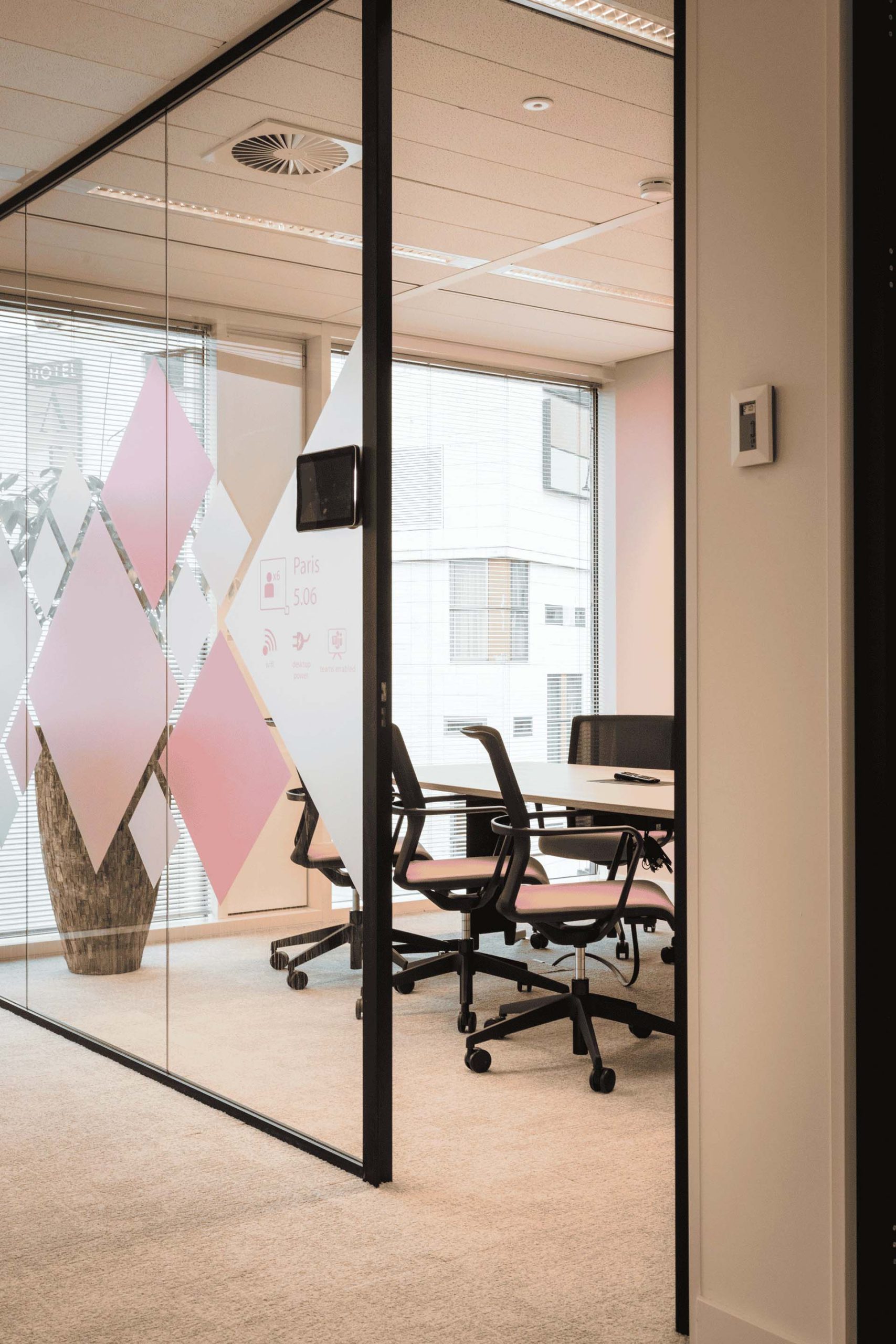 Salle de réunion avec vitre stickée de formes carré rose et blanche