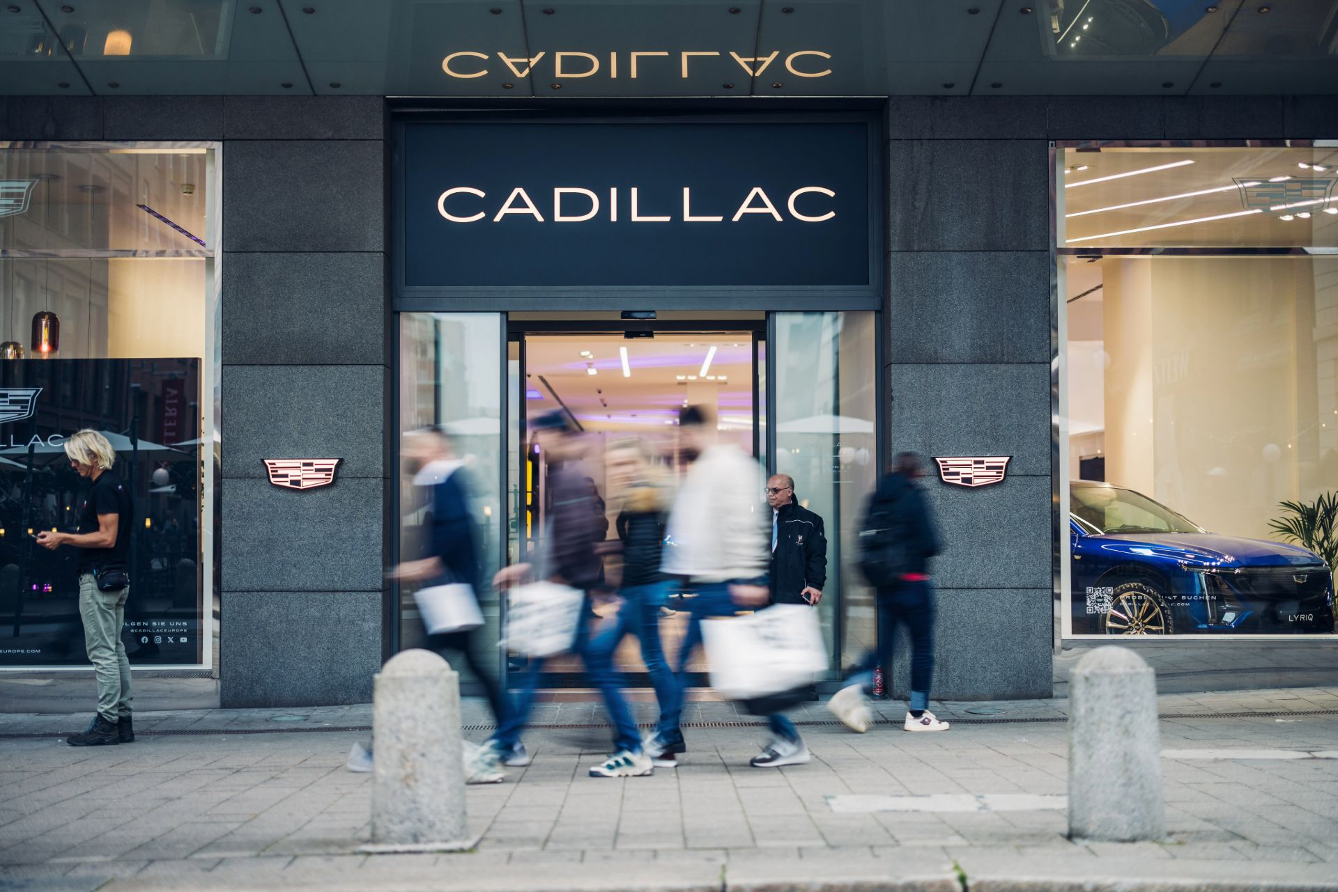 Vue de la boutique depuis la rue avec le nom de la marque au centre et une entrée avec des portes automatiques. De chaque côté des logos de la marque encadrent l'entrée.