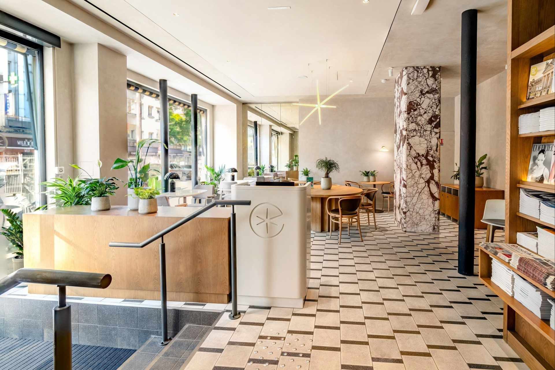 Intérieur du lounge, carrelage noir et blanc, poutre en marbre, murs blancs, mobilier en bois clair