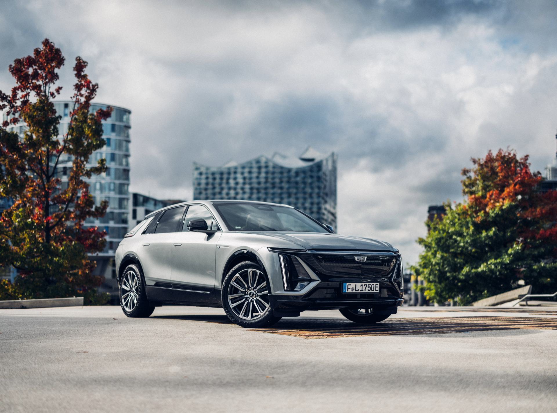 Photo d'une Cadillac sur une esplanade avec des arbres et des tours de bureaux derrière.