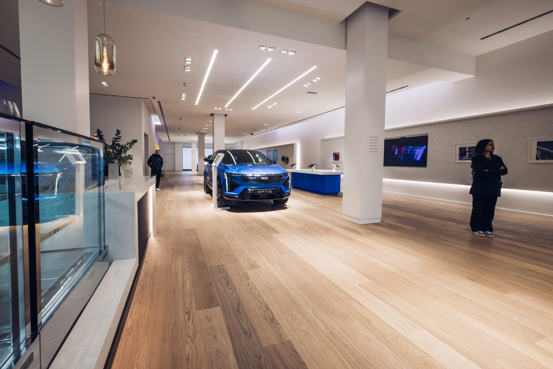 Vu du showroom avec un véhicule bleu exposé, à gauche un accueil et à droite au fond un stand de tablettes.
