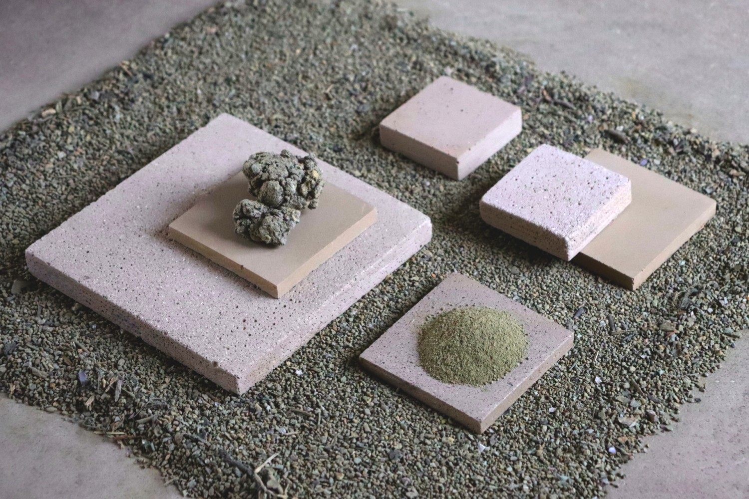 Matières posées sur des plaques de béton elles mêmes posé sur des fines billes vertes kaki.
