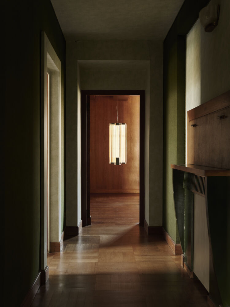 Couloir vert kaki, parquet en bois qui donne sur une pièce entièrement en bois avec un lustre desig