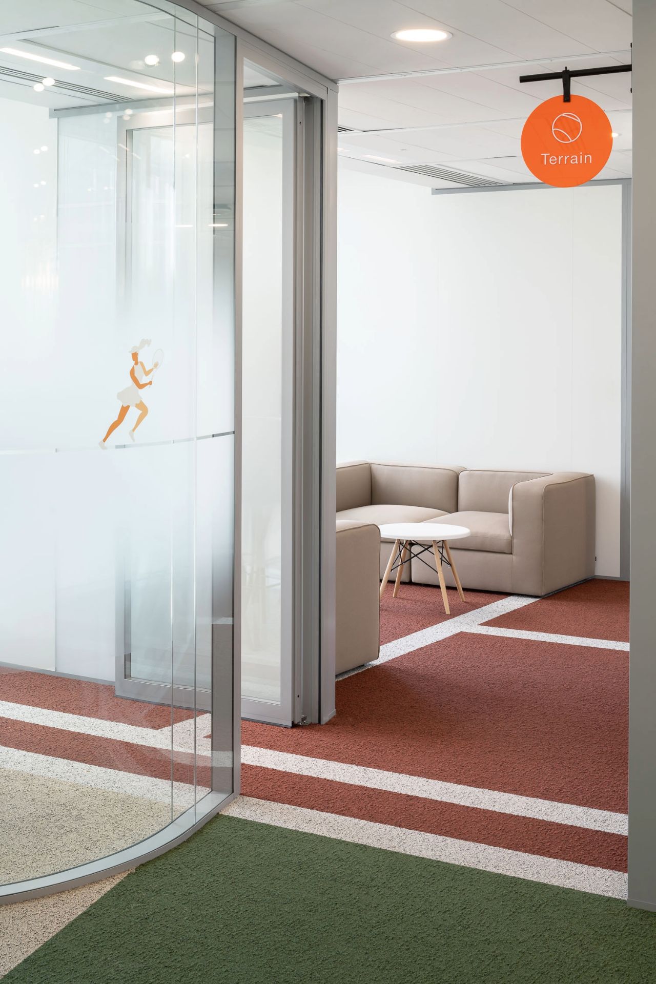 Photo d'un canapé an arrière-plan avec moquette ocre et verte style tennis plus une lumière orange ronde au plafond.