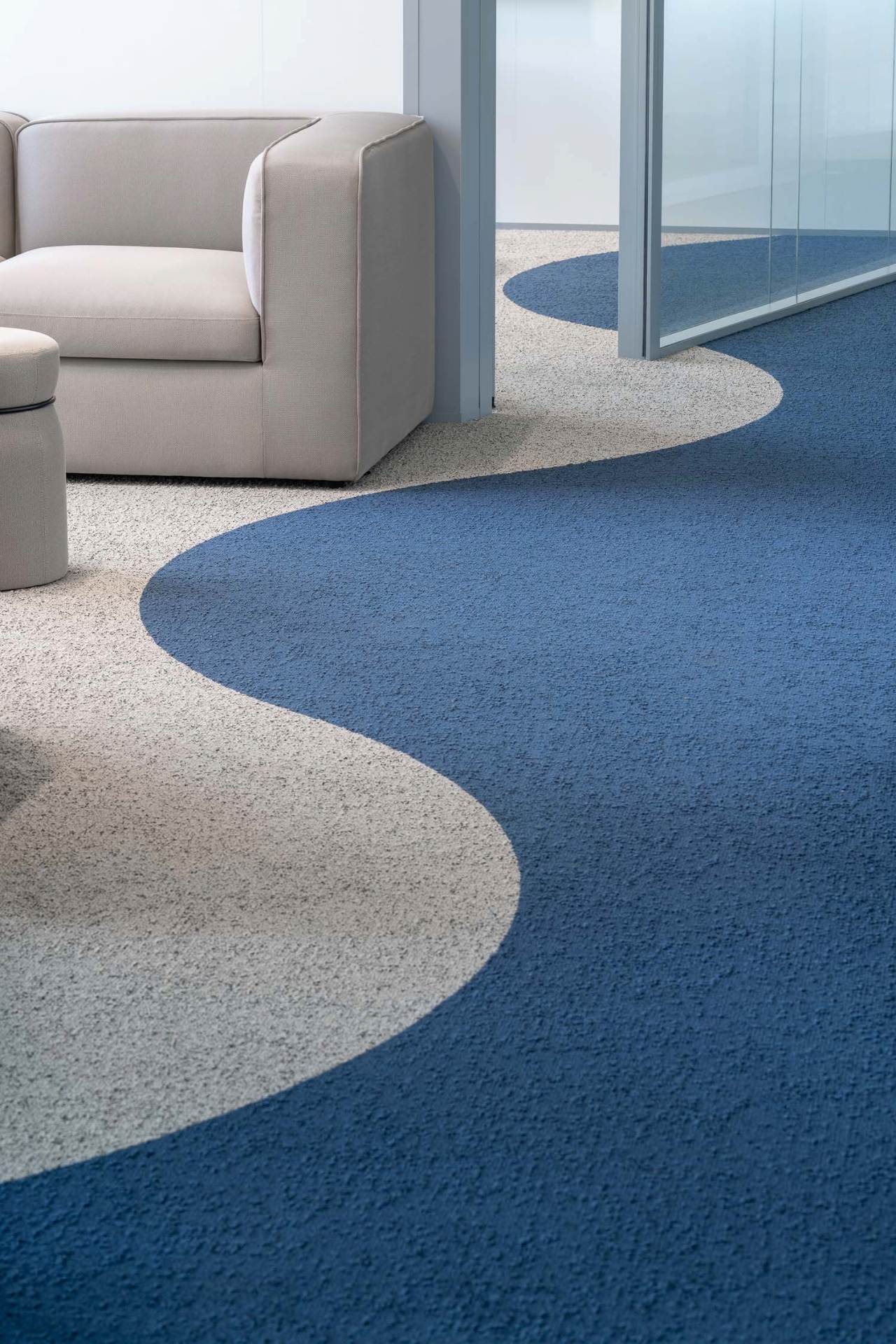 Photo de canapés gris avec un motif de vagues bleues et grises au sol.