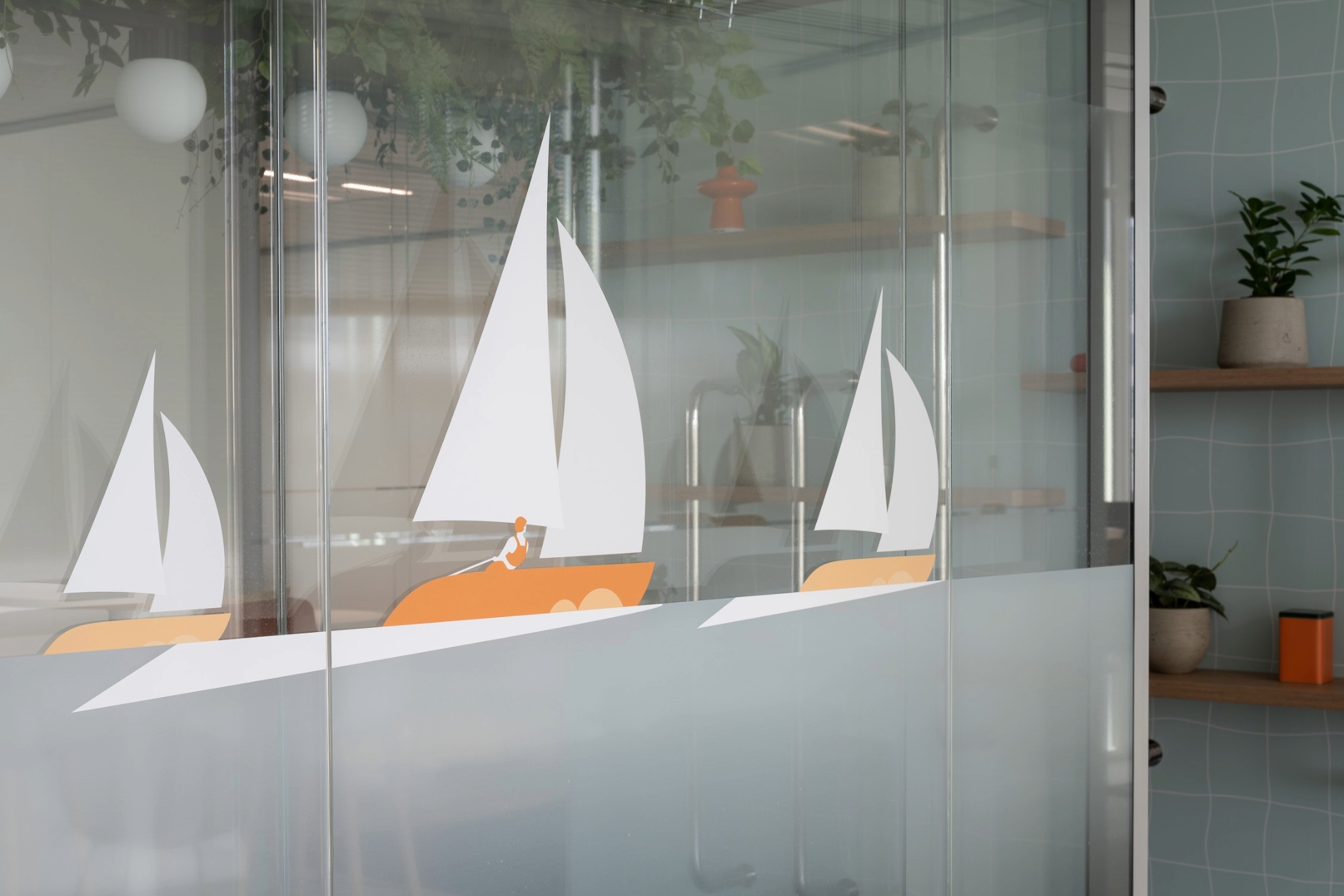 Photo d'une vitrophanie représentant des bateaux à voile orange et blanc.