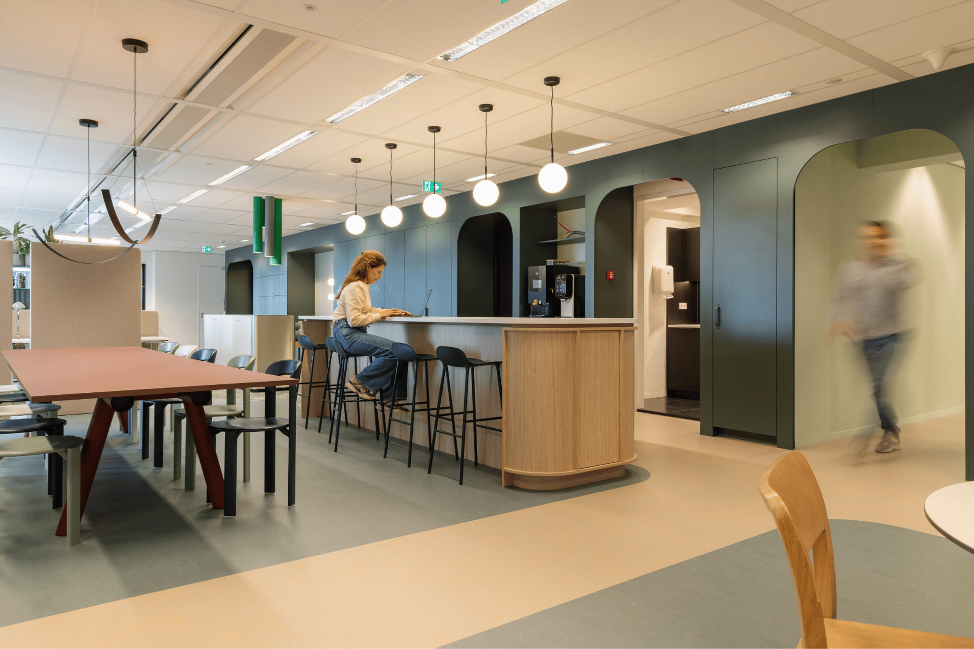 Espace de restauration avec un bar et une personne travaillant sur son ordinateur.