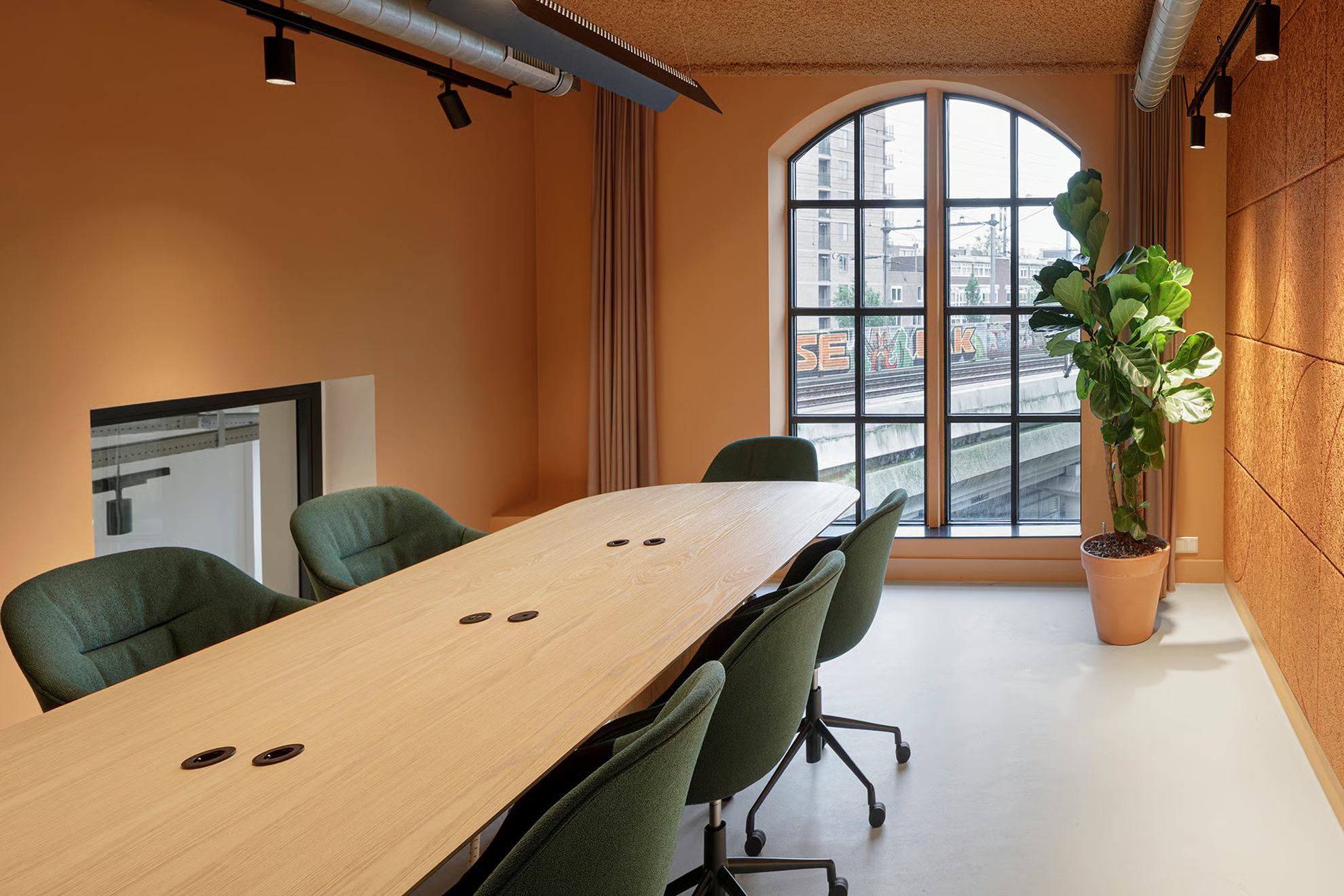 Salle de réunion avec une table et des murs marron + fenêtre au fond.