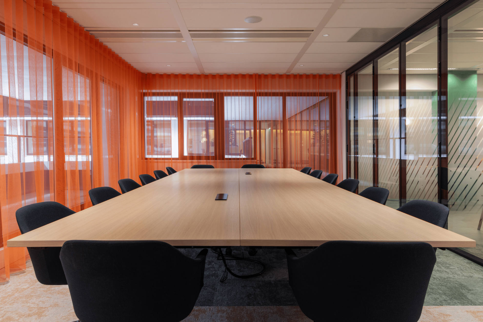 Table de réunion rectangulaire avec des chaises + murs rouges.