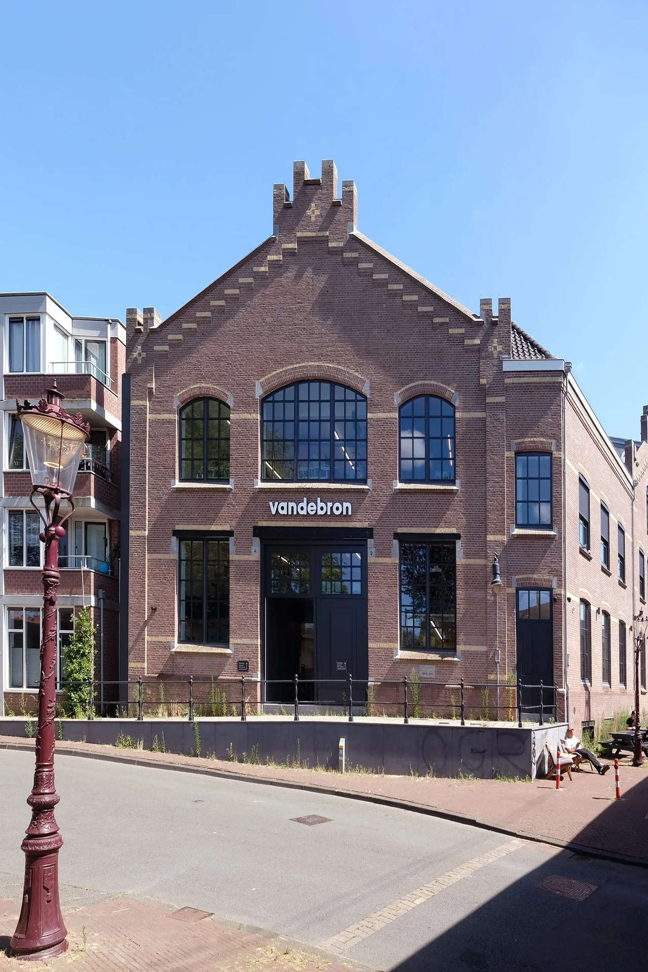 Photo du bâtiment dans un style du 19ème siècle en brique rouge vu de l'extérieur avec le logo de l'entreprise.