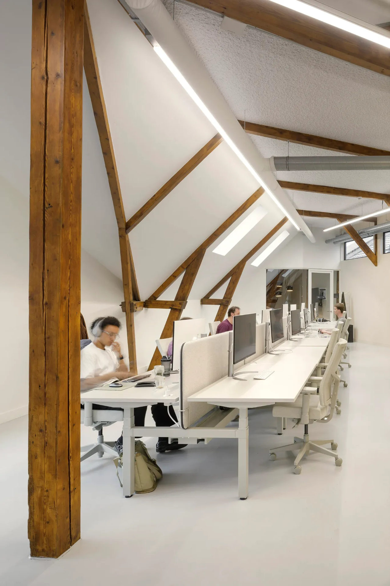 Vue des combles avec une rangée de postes en blanc et une charpente en bois avec des murs blancs.
