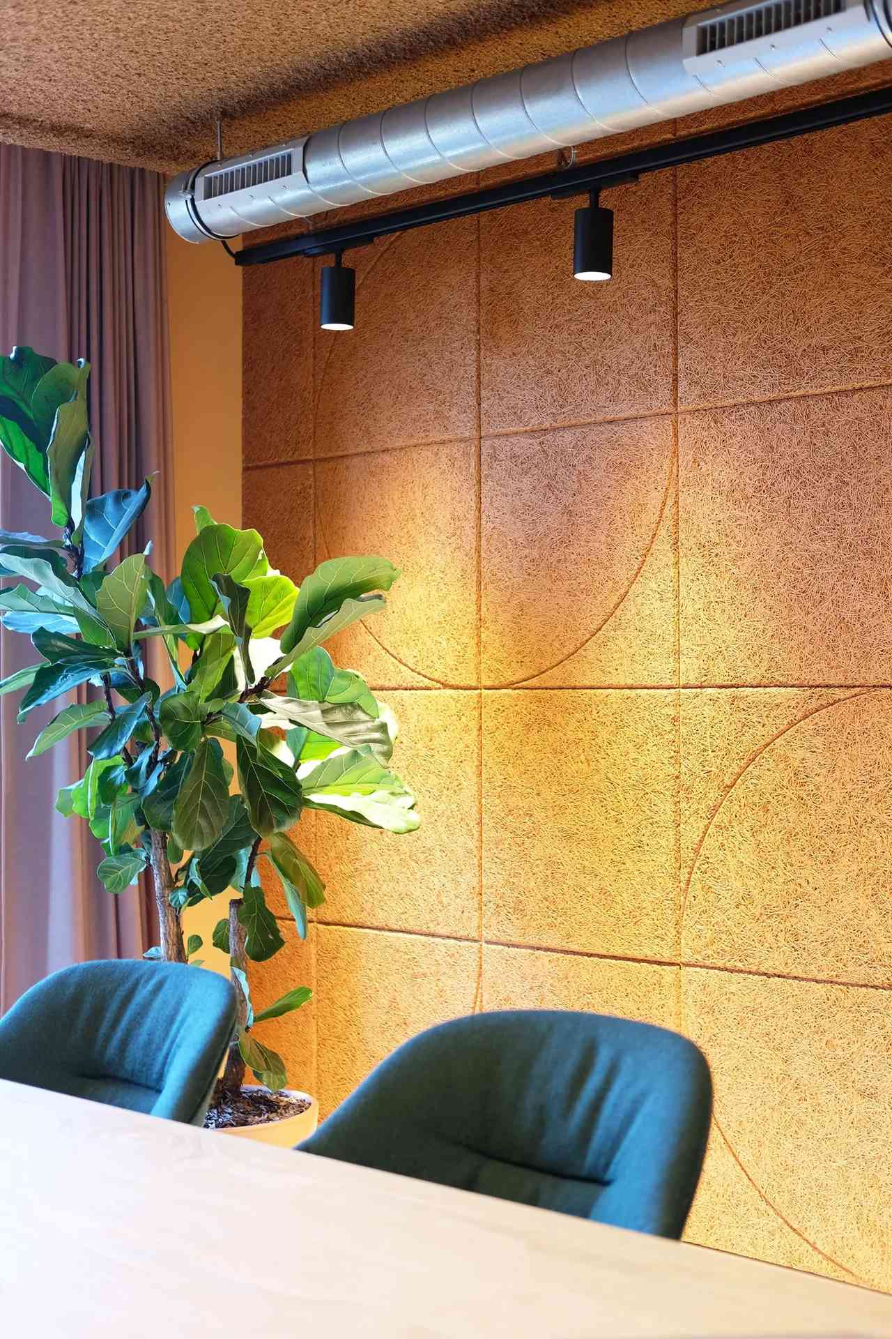 Deux chaises avec une plante à gauche et une rangée de LED éclairant les motifs muraux.