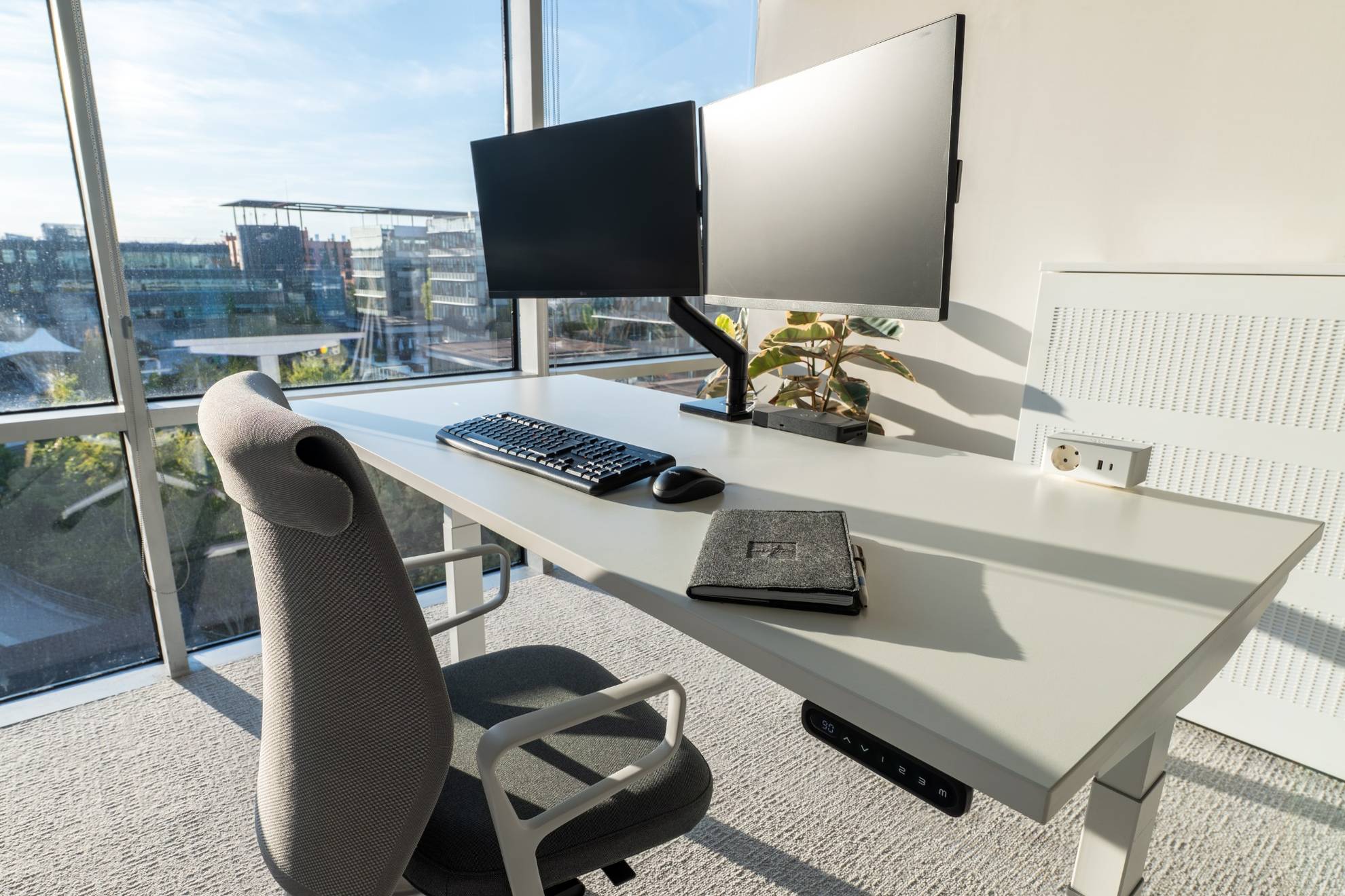 Gros plan sur un bureau avec un carnet et une vue au fond sur le parc.