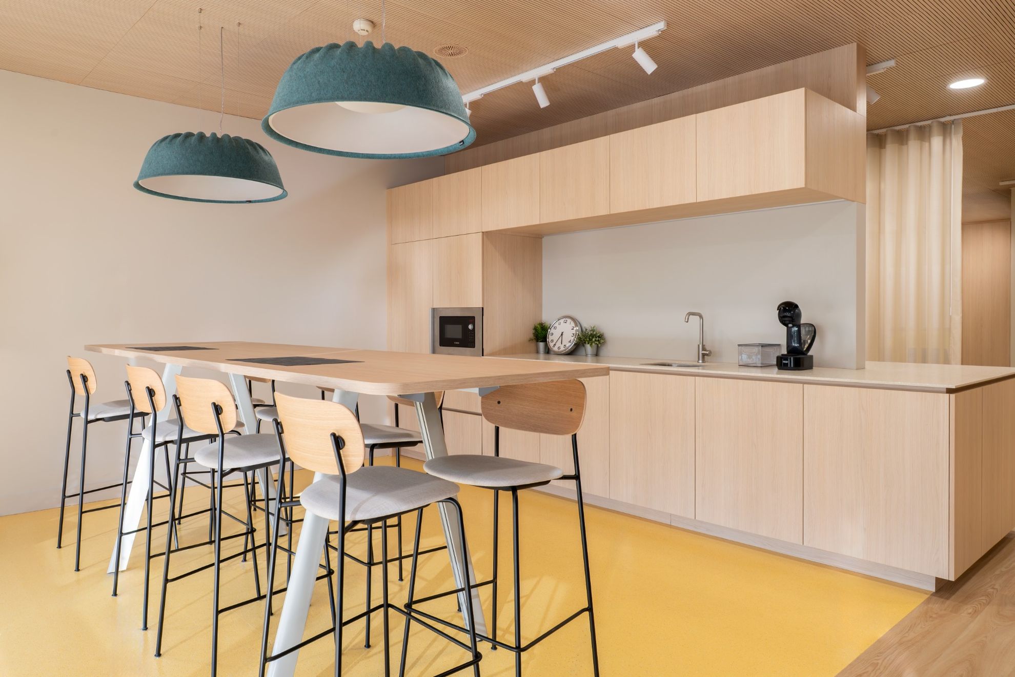 Caféteria avec une table haute et une cuisine ouverte en bois claire.