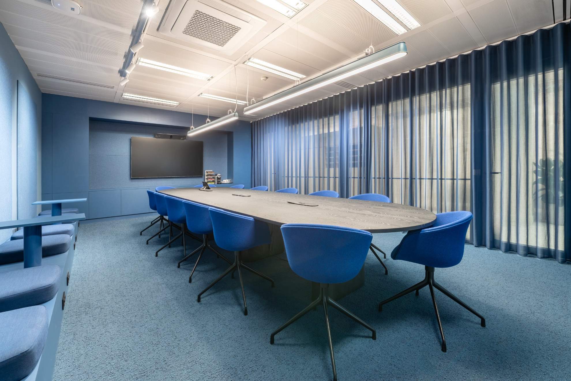 Salle de réunion bleue avec une table marron et des chaises bleues.