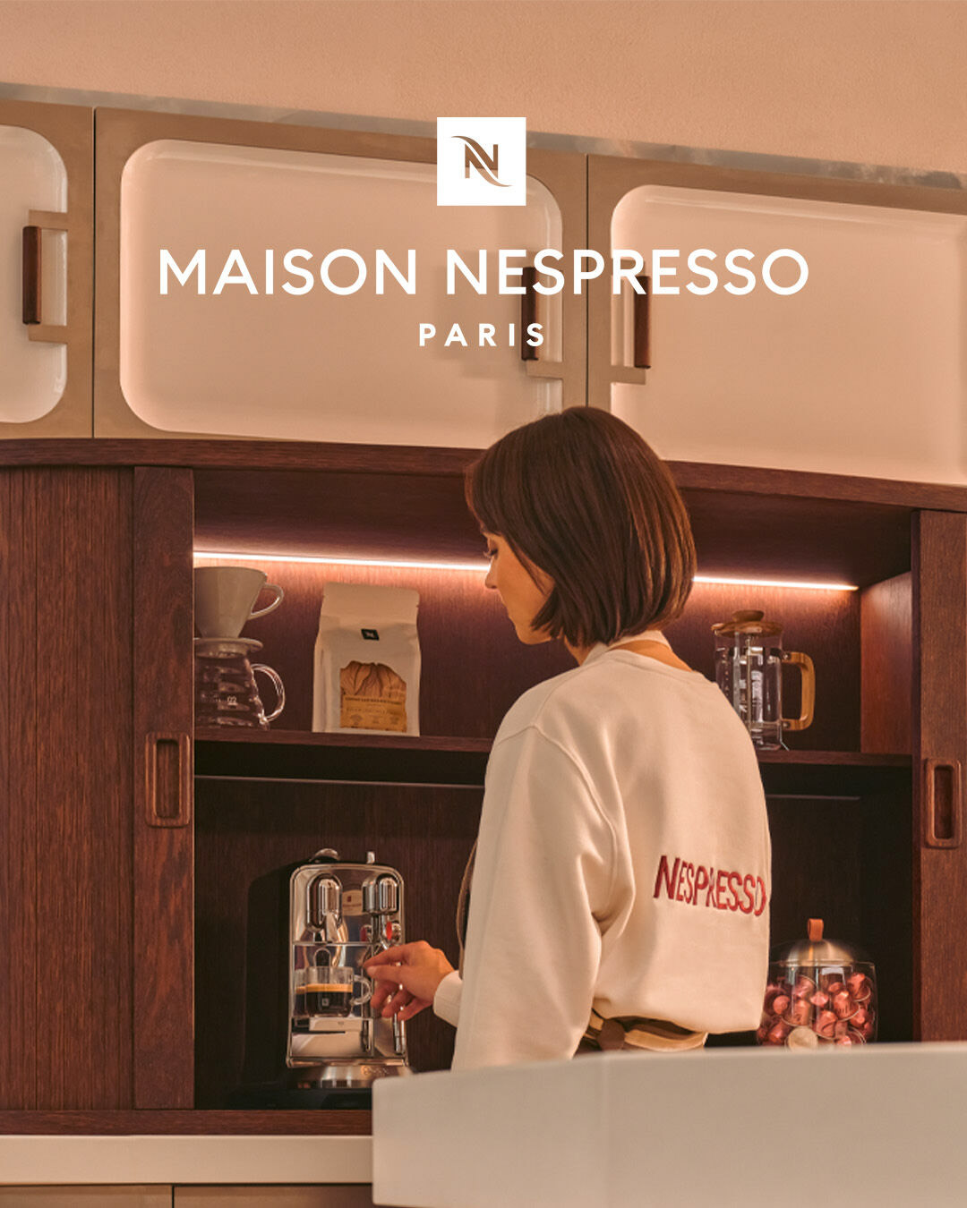 Une fille se faisant un café avec un pull nespresso.