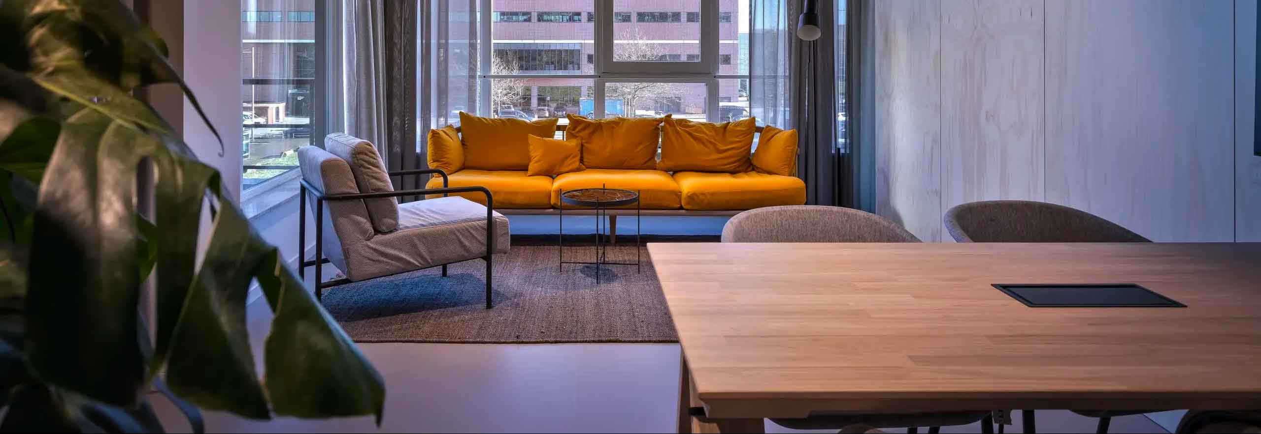 Photo avec au premier plan un table et des chaises, au second plans un canapé jaune