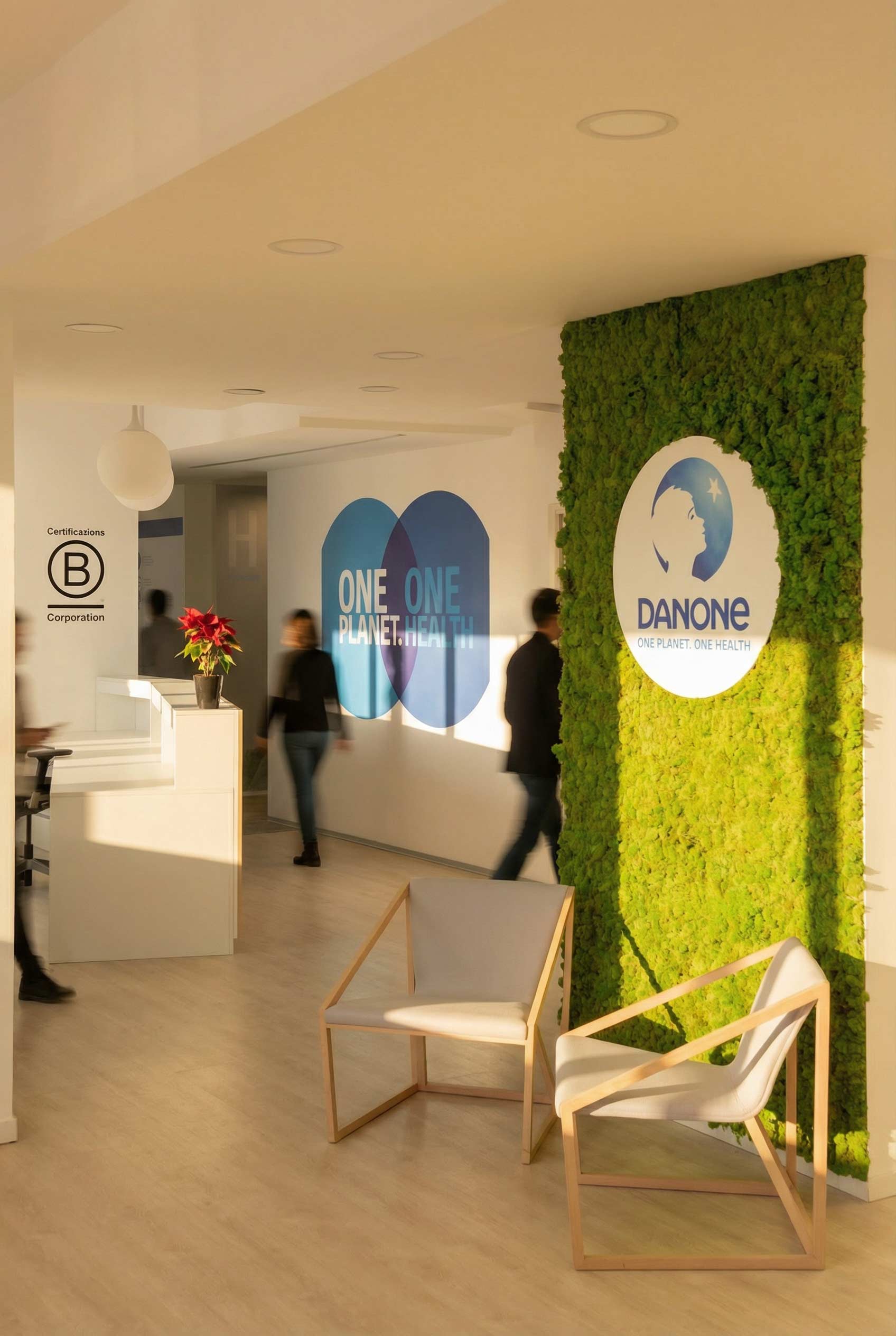 Le hall d'accueil arborant un mur végétal avec le logo Danone, des fauteuils design blancs et une signalétique "One Planet. One Health".