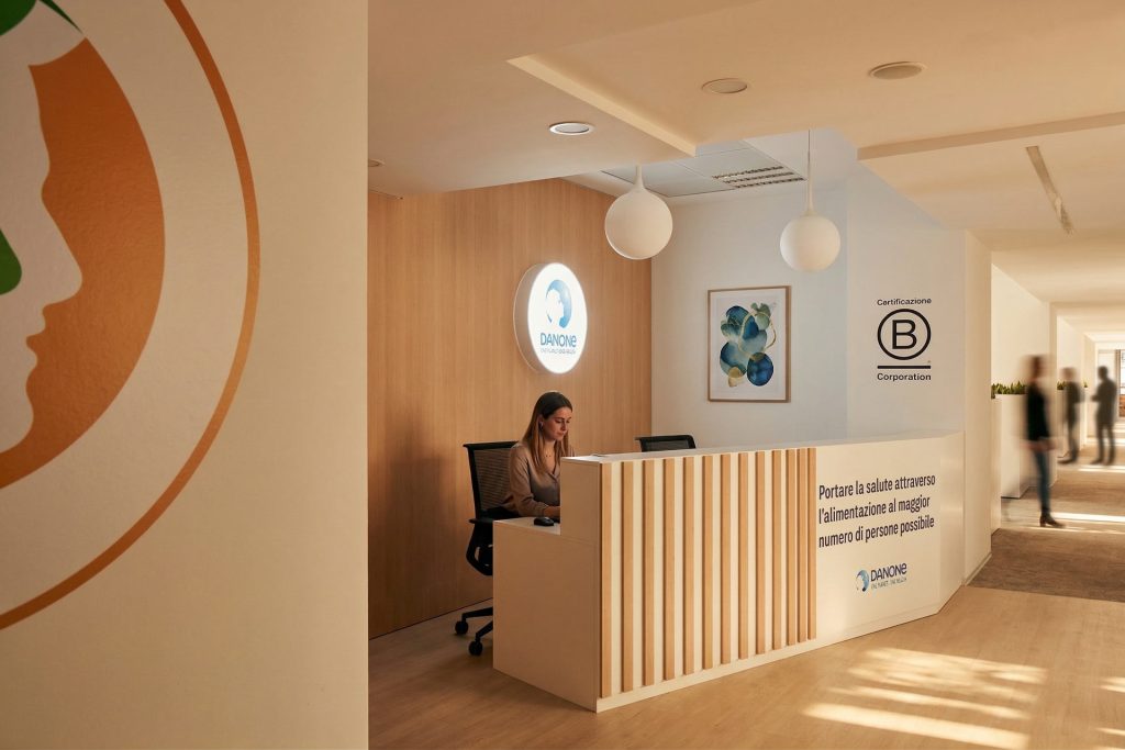 Une vue de la réception épurée avec un comptoir en bois et blanc, affichant un message de mission d'entreprise et le logo B Corp.