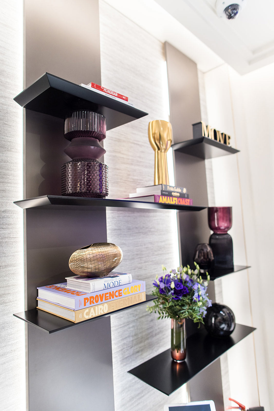 Un plan rapproché sur les étagères murales ornées de livres d'art, de vases colorés et du logo « MOVE » emblématique de la marque.