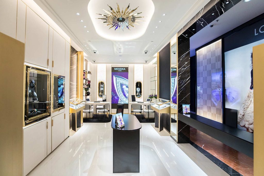 Une perspective symétrique de l'allée centrale menant à un grand écran numérique et des espaces de vente privés de chaque côté.