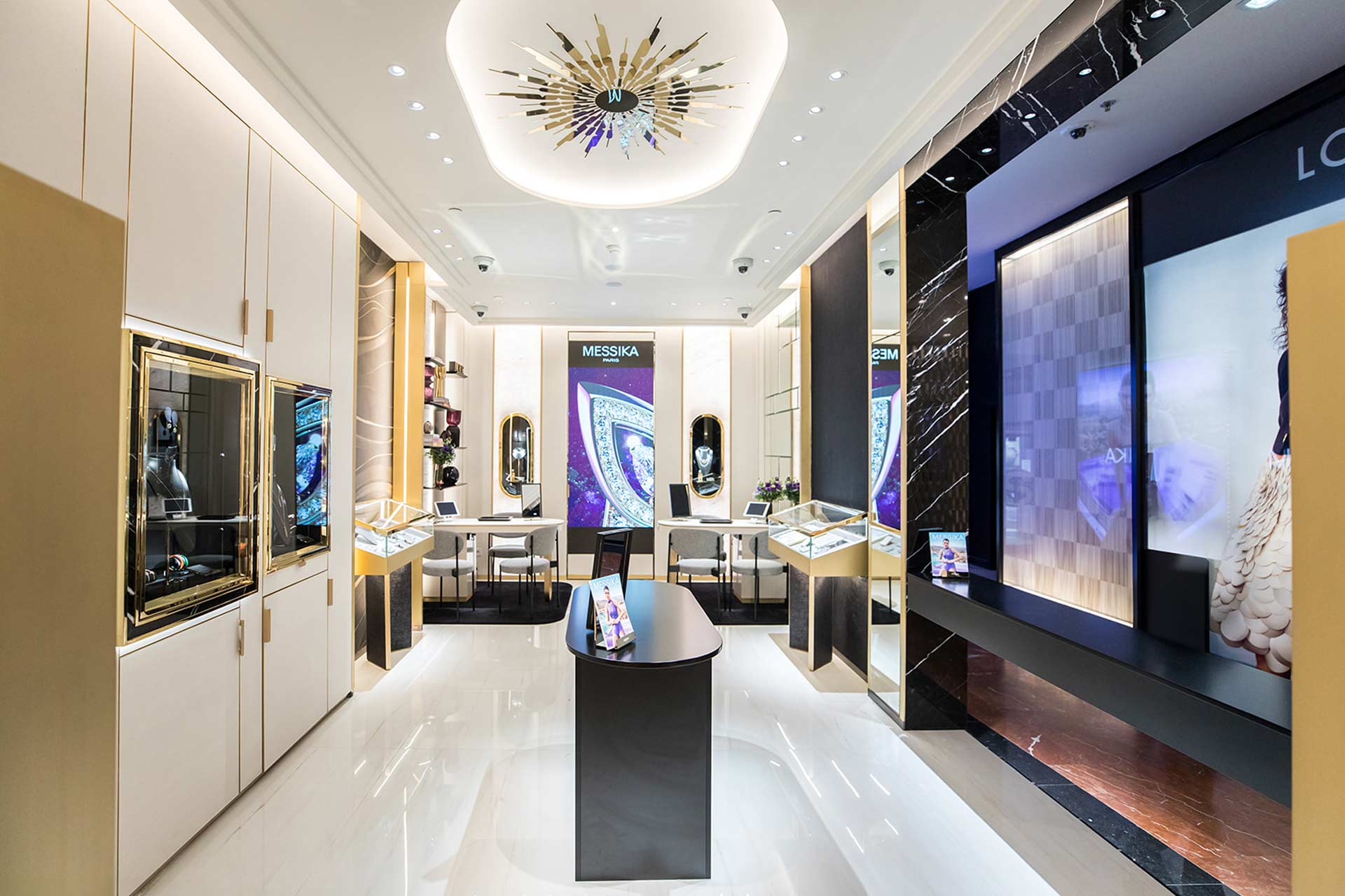 Une perspective symétrique de l'allée centrale menant à un grand écran numérique et des espaces de vente privés de chaque côté.